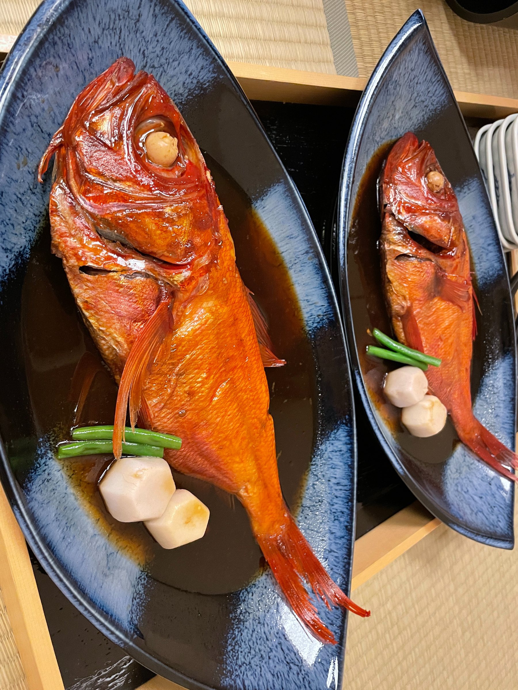 Two whole kinmedai, glossy with their simmering sauce.