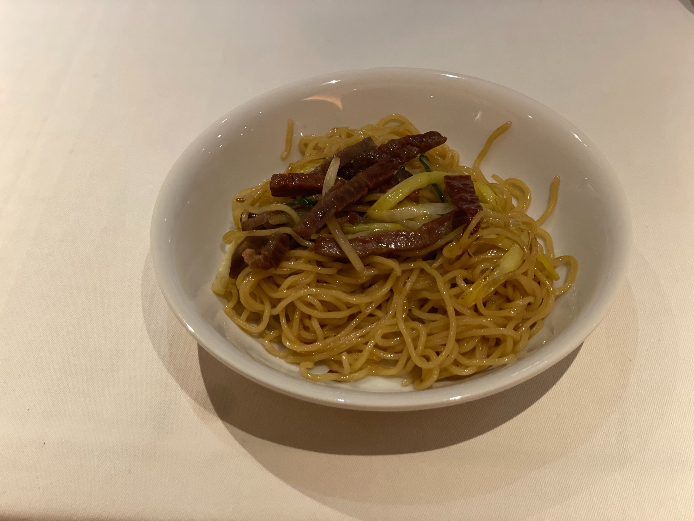 Fried noodles topped with strips of dark, dried char siu.