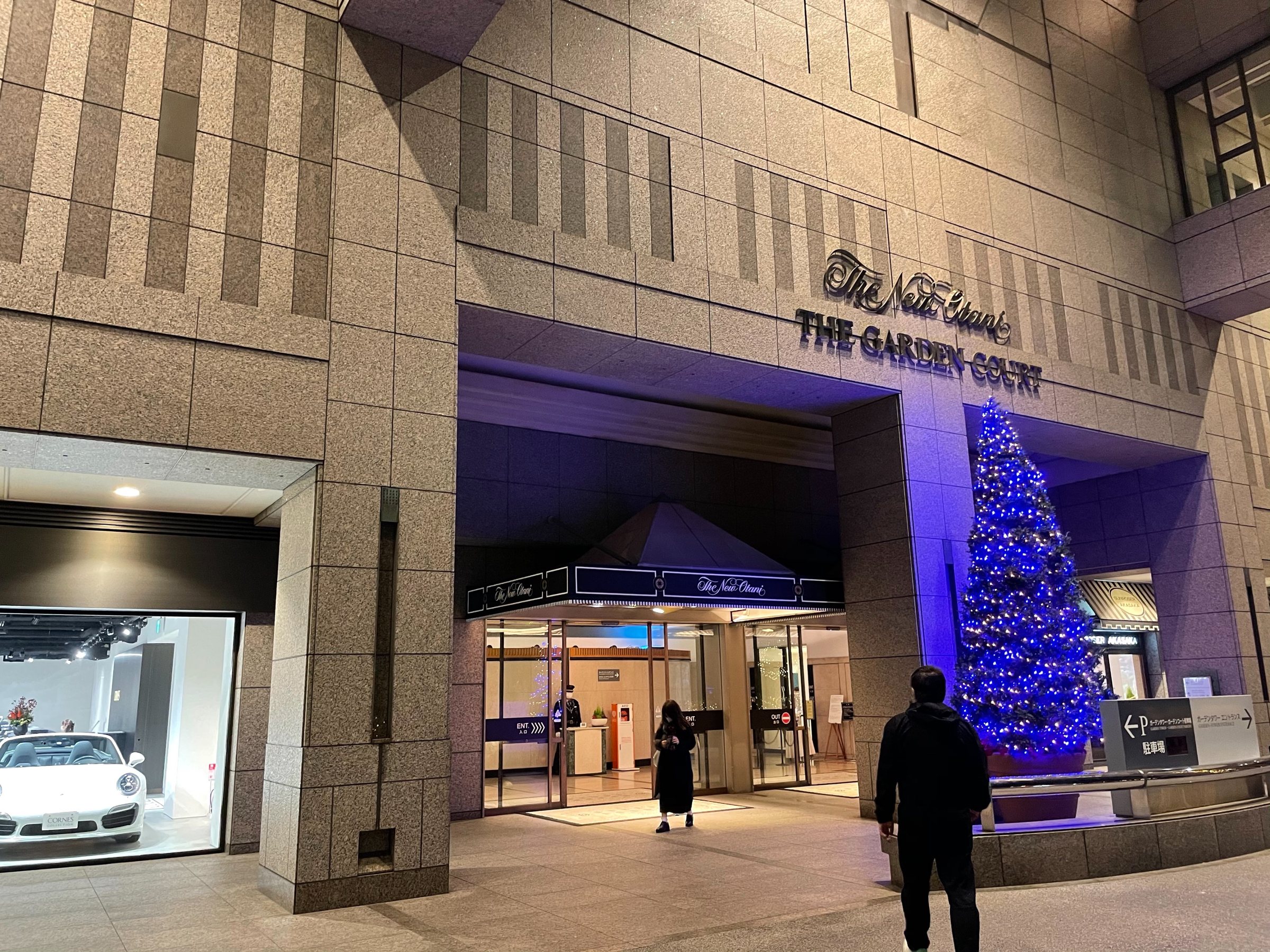 The Garden Court entrance at night, a blue-lit Christmas tree beside the doors.