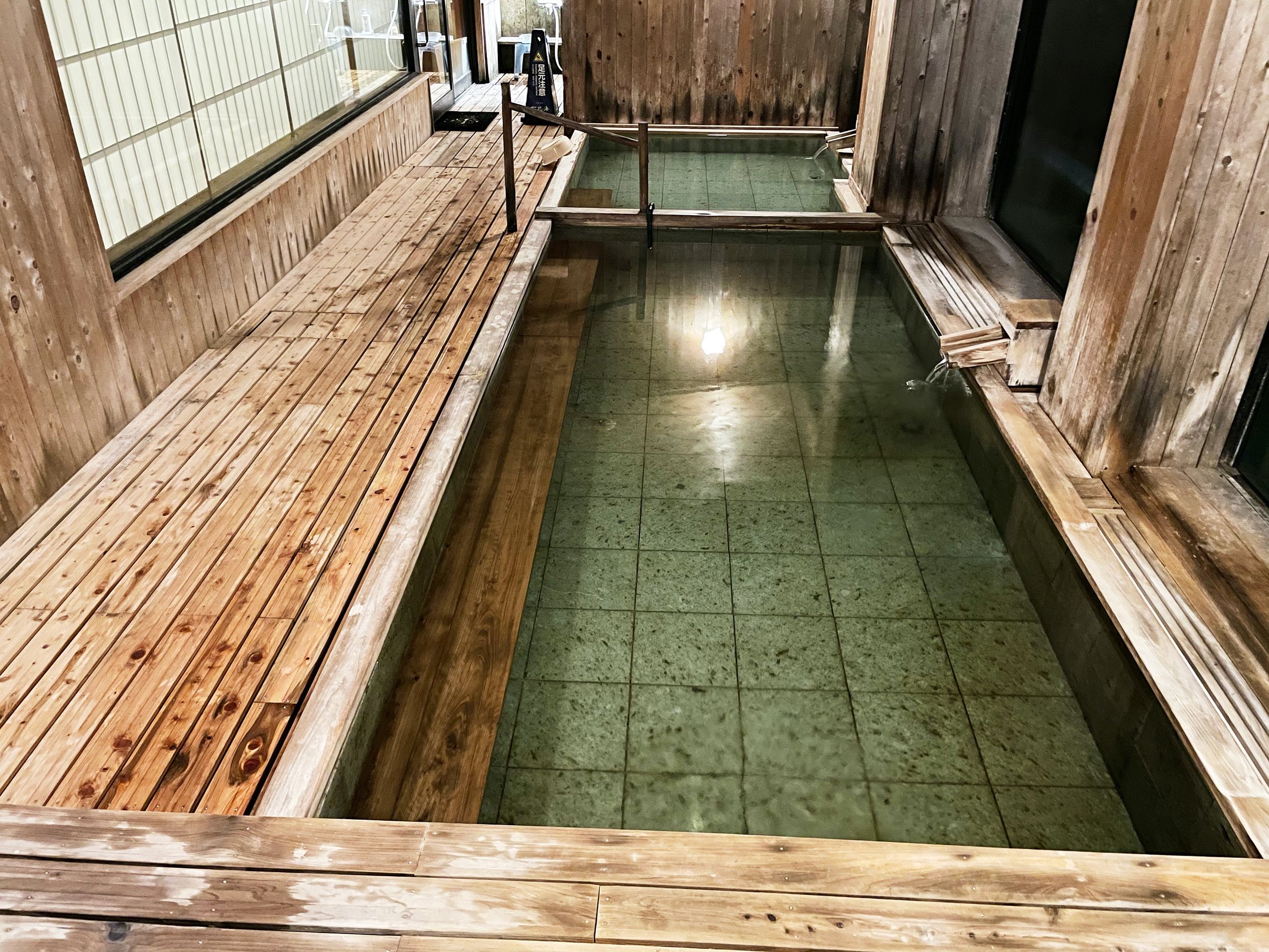A long, tiled bath edged in timber decking.