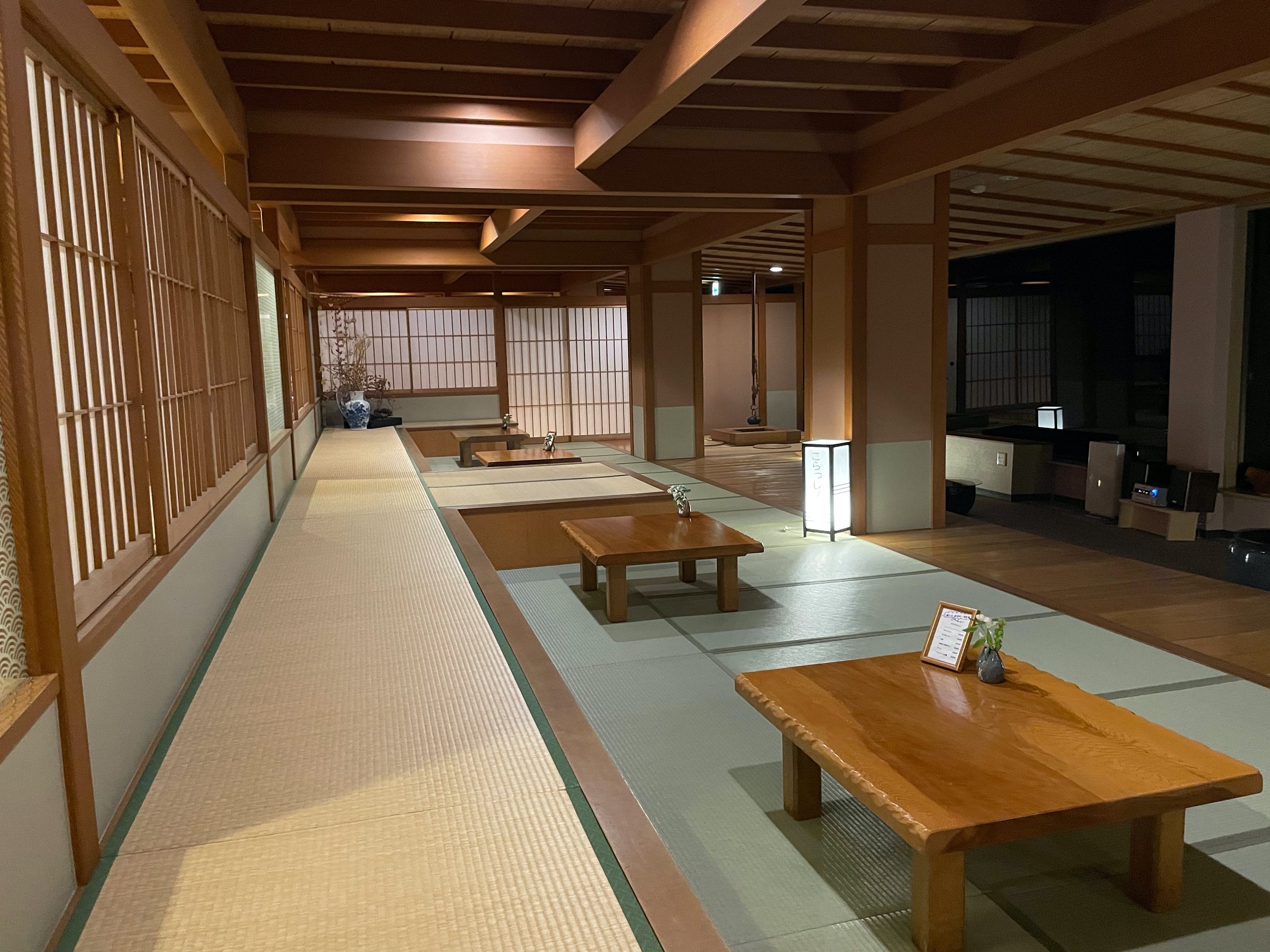 The long tatami lounge, low tables set beneath the lanterns.