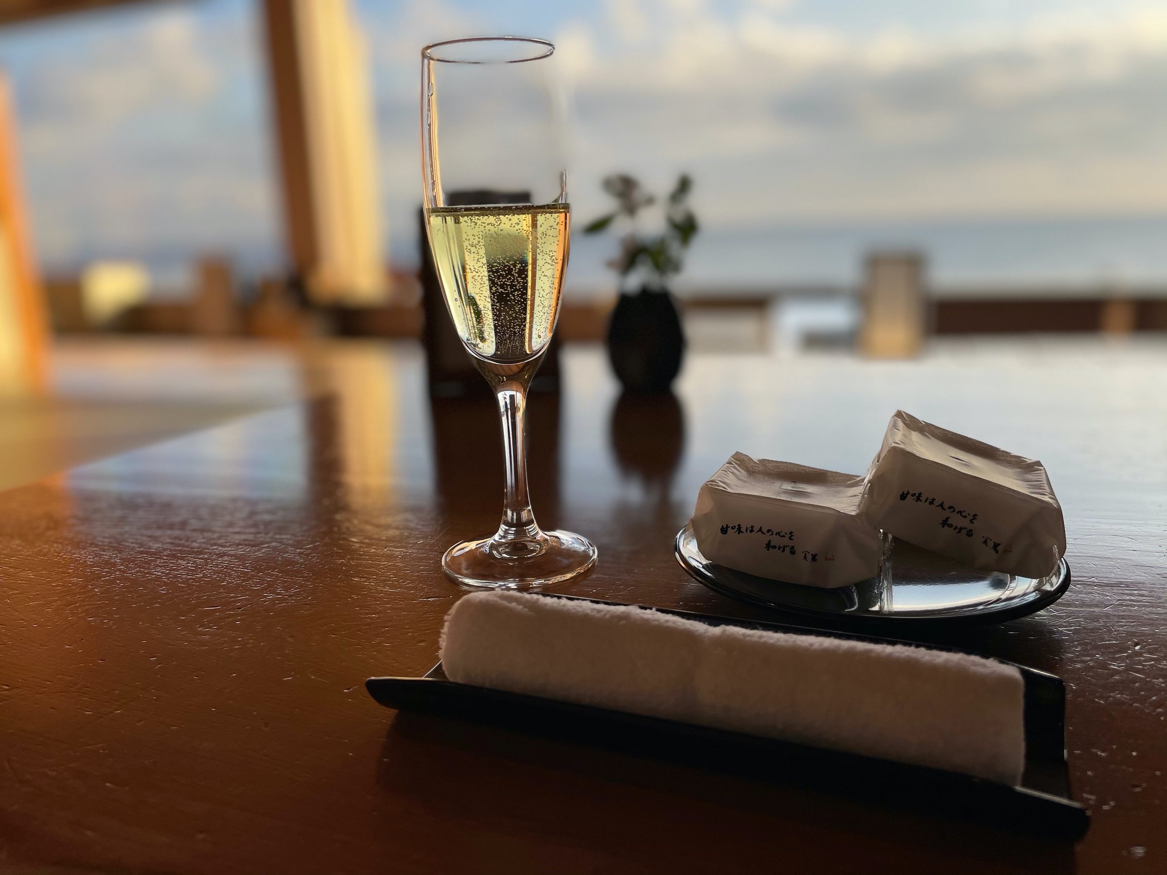 Welcome champagne and wrapped sweets, with the sea beyond the glass.