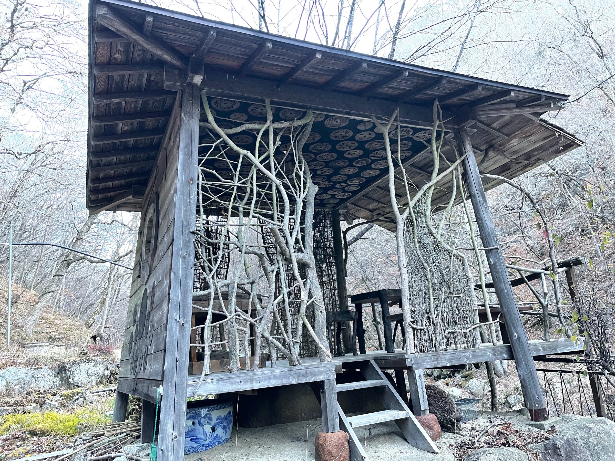 A pavilion woven with twisting branches beside the walking path.