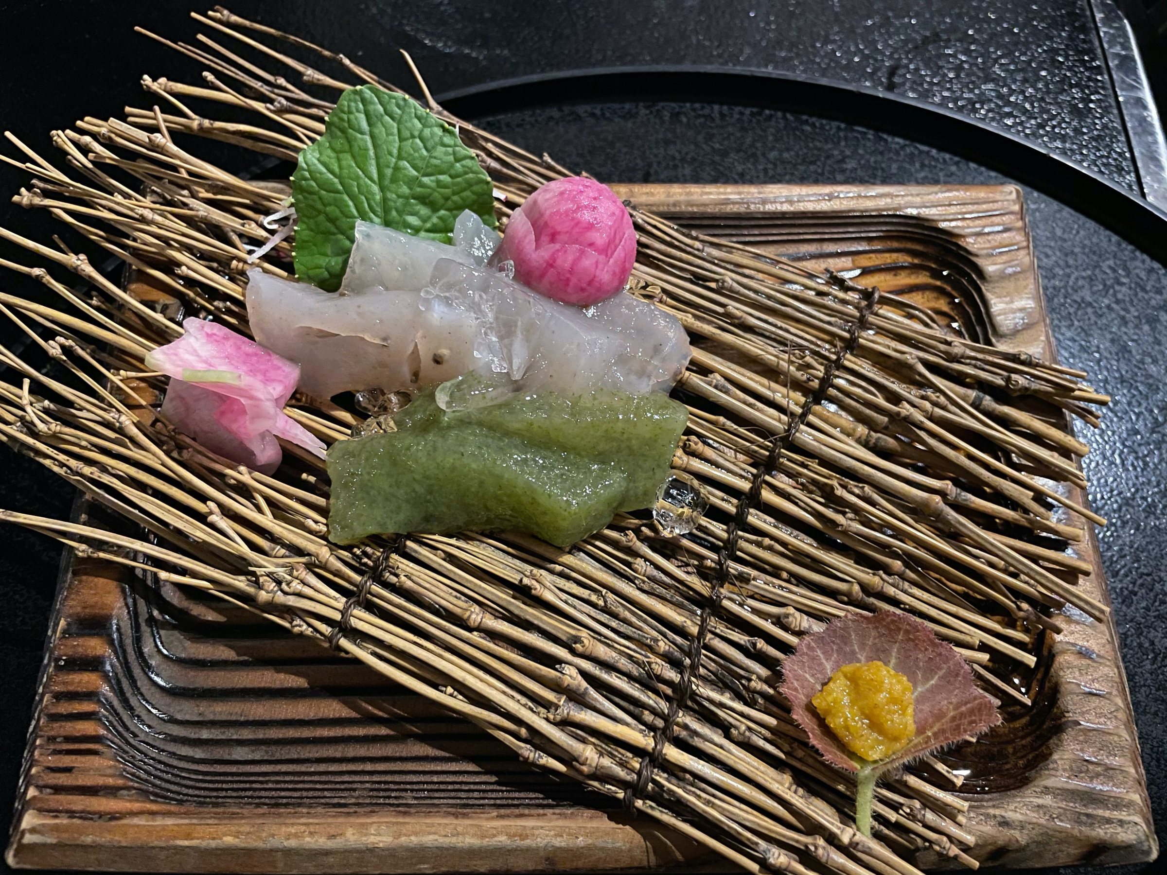 Handmade sashimi konnyaku, arranged on a mat of twigs.