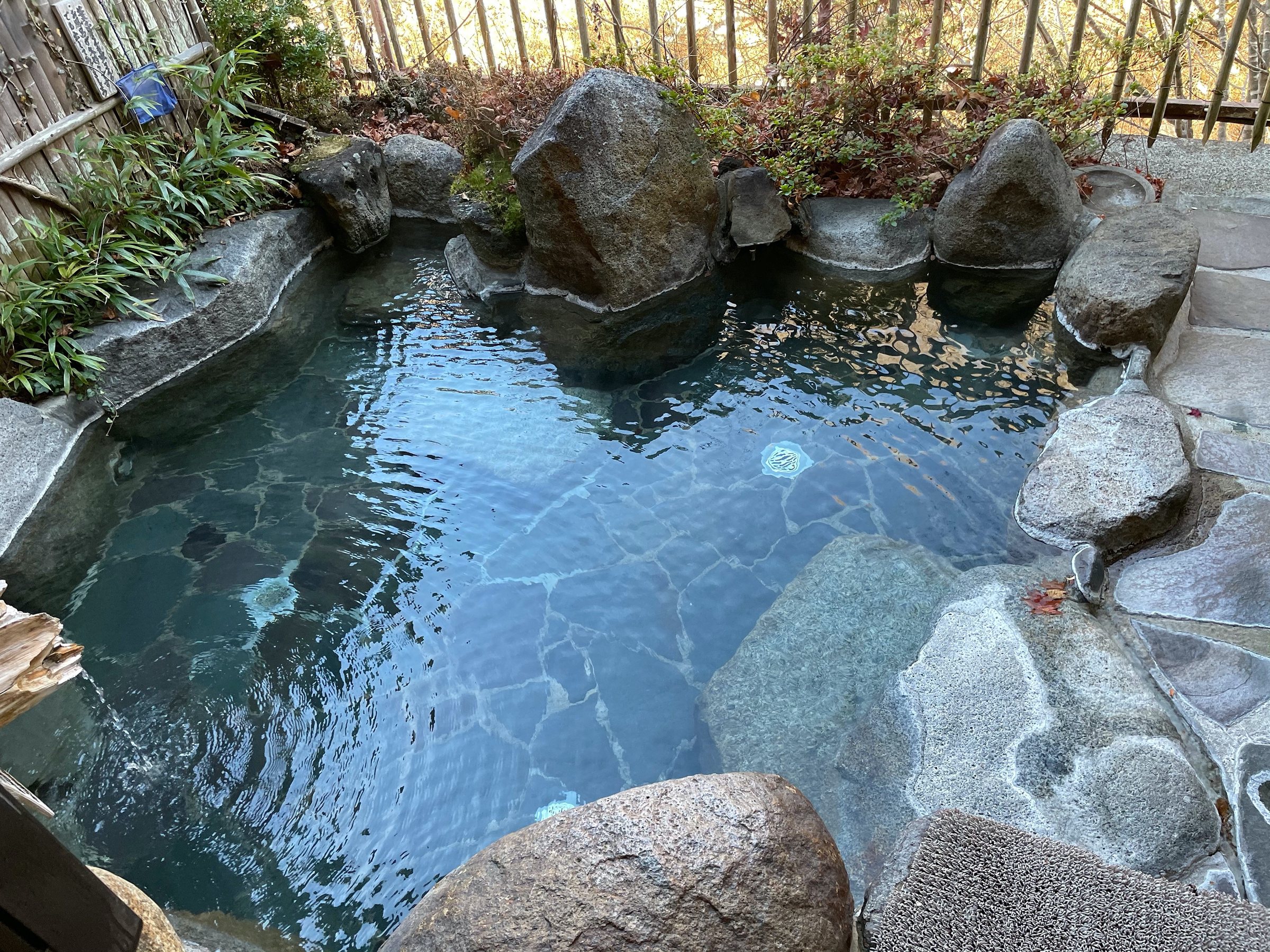 The rock-lined open-air bath, its water clear and blue.