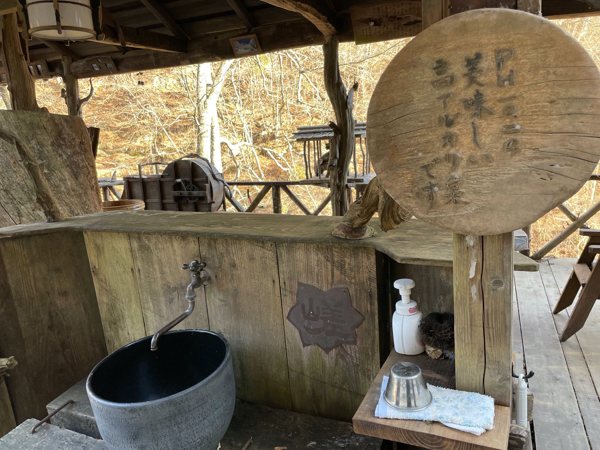A spout of drinkable natural water beside a carved wooden sign.