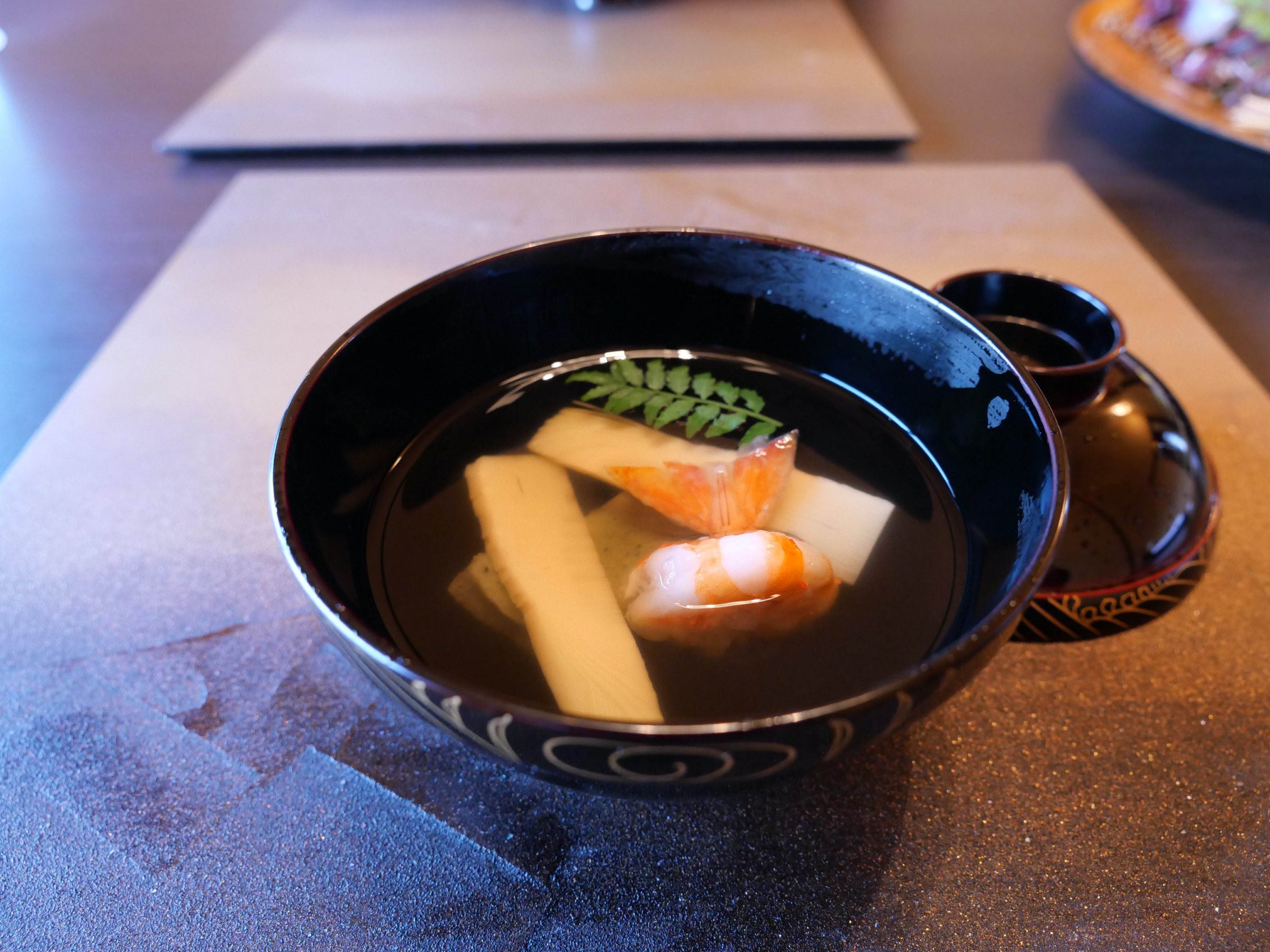 The soup course in a black lacquer bowl.