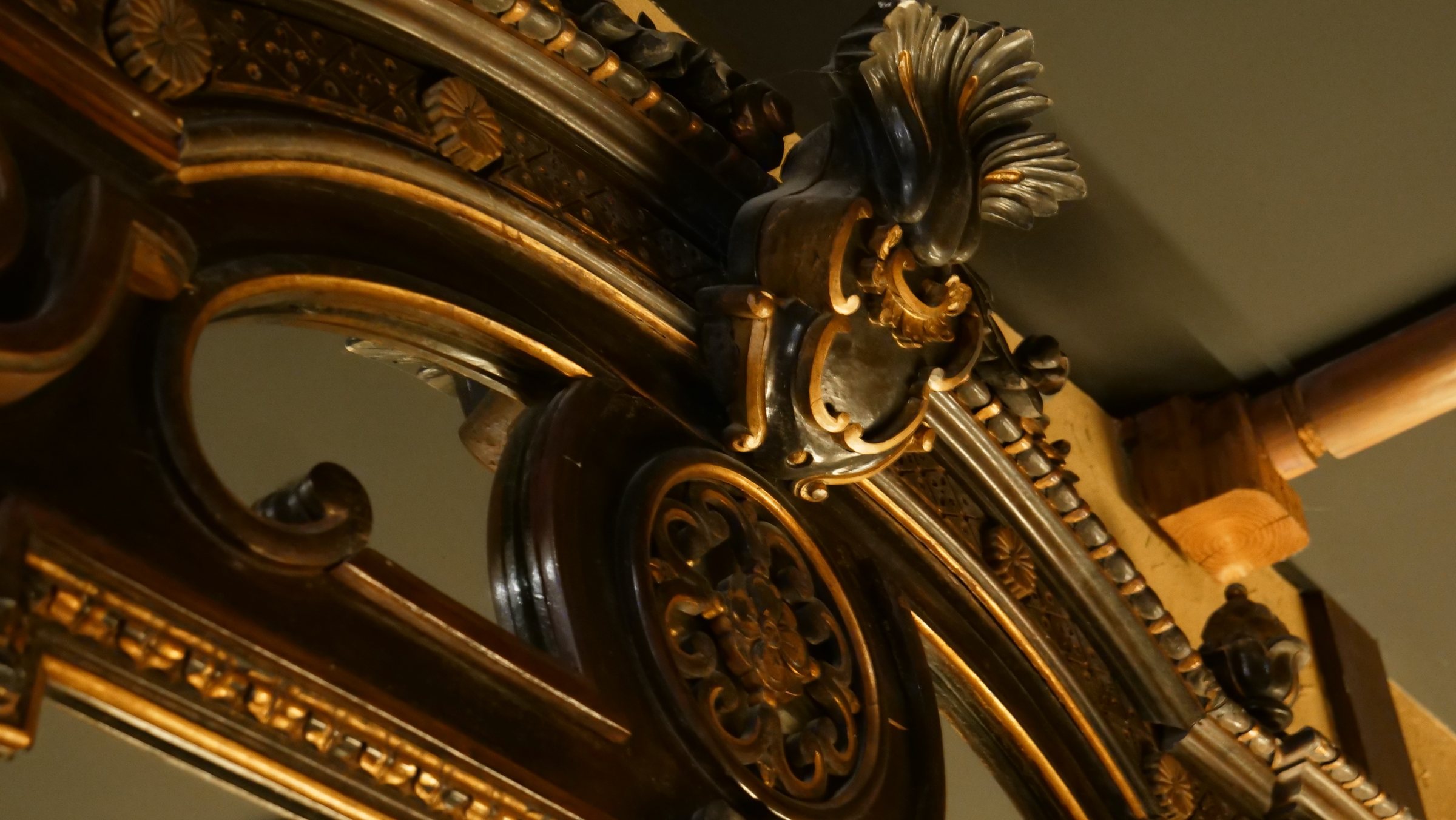 The mirror's gilded crest, close up.