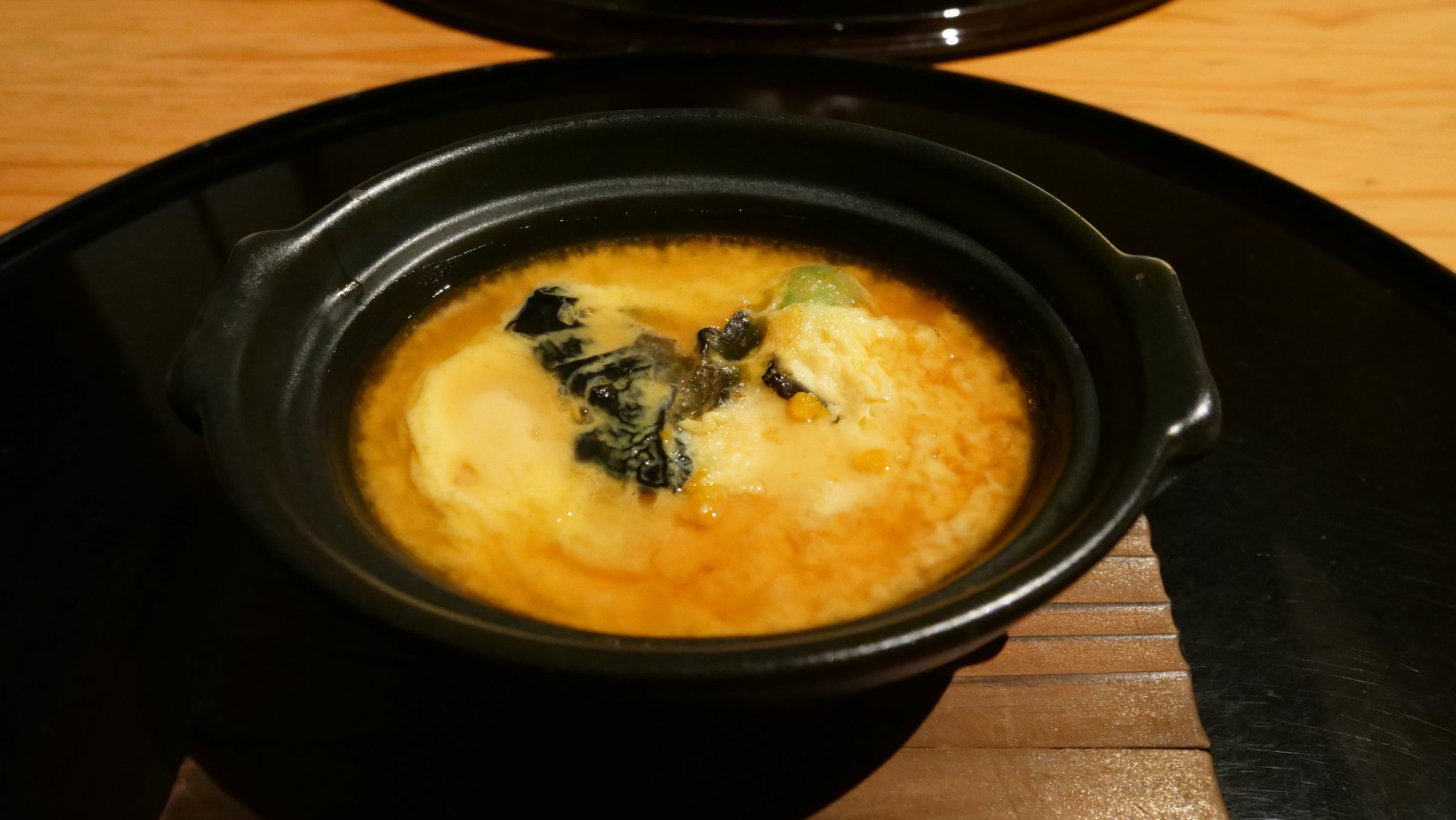 Cod milt, lily bulb and ginkgo set in egg, in a small earthenware pot.