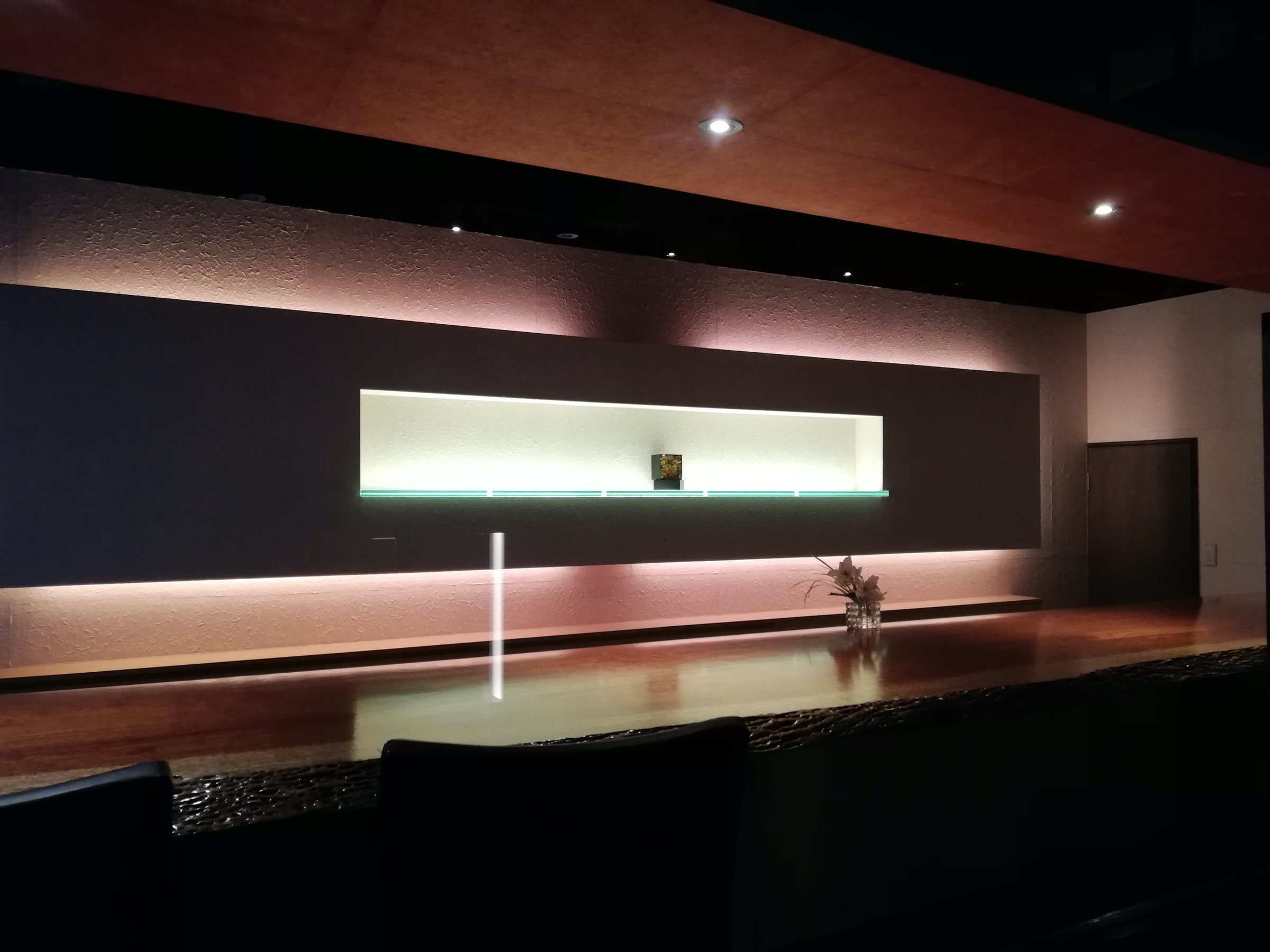 The bar, its counter lit in a soft red glow.