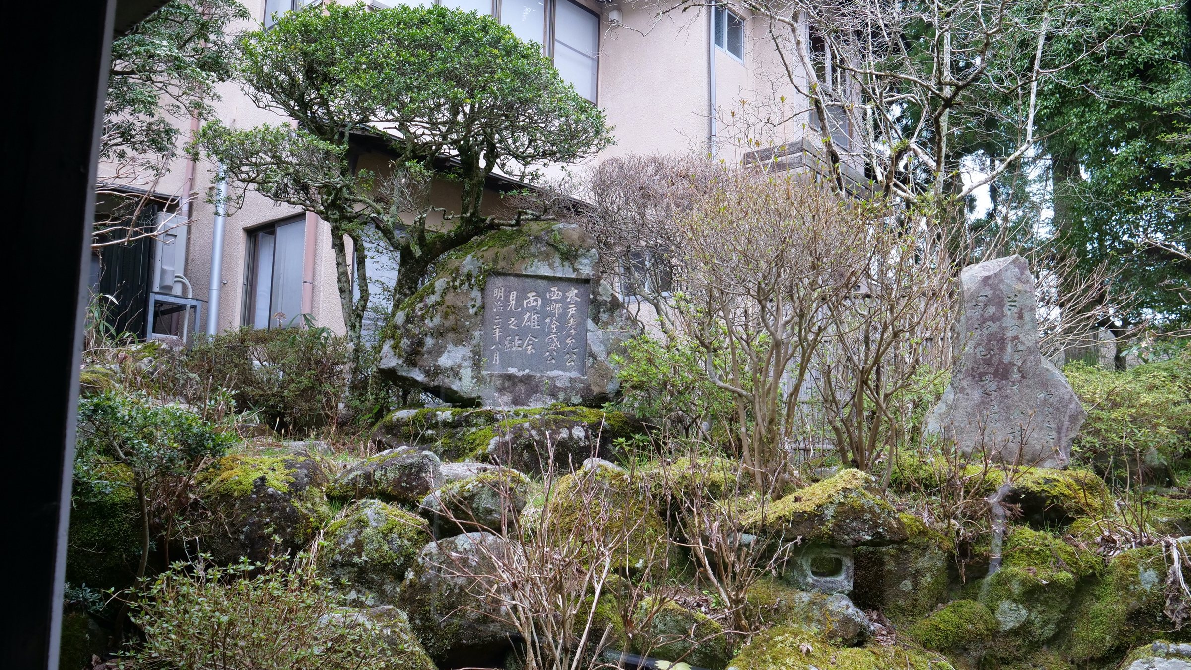 The memorial stone among moss, rocks and pines.