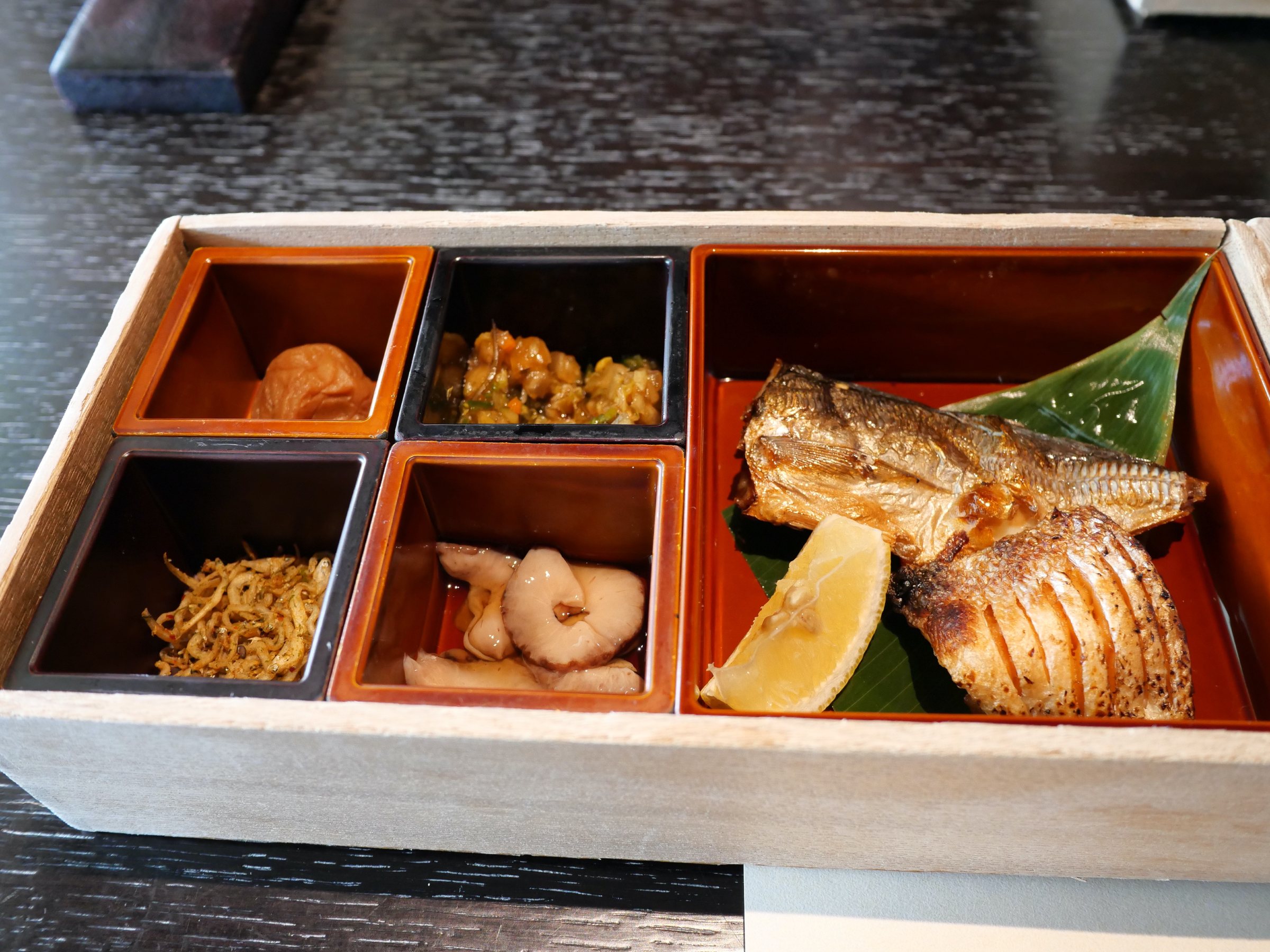 The opened box: small compartments and grilled dried fish.
