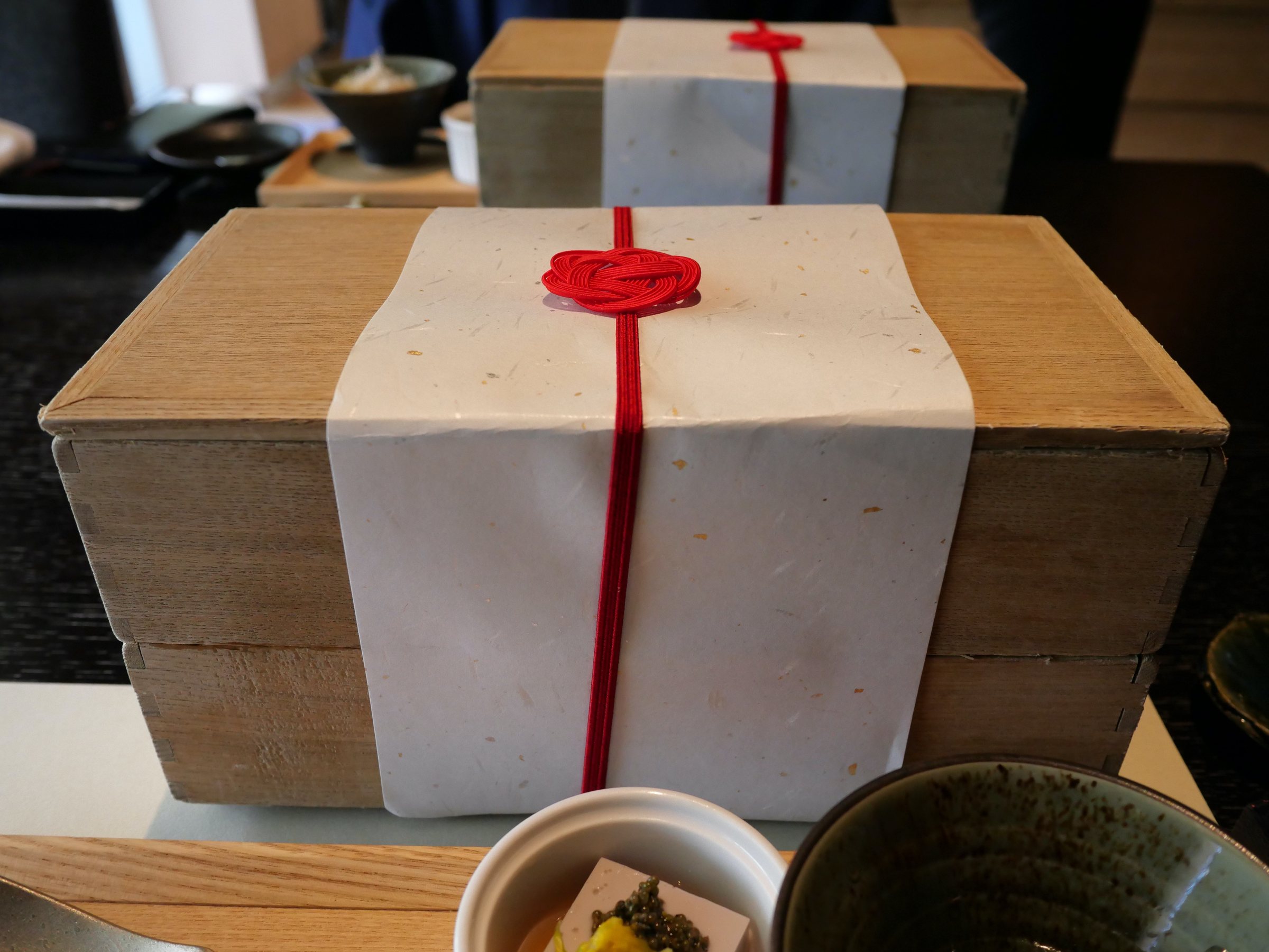 The breakfast box, wrapped in paper and tied with a red cord.