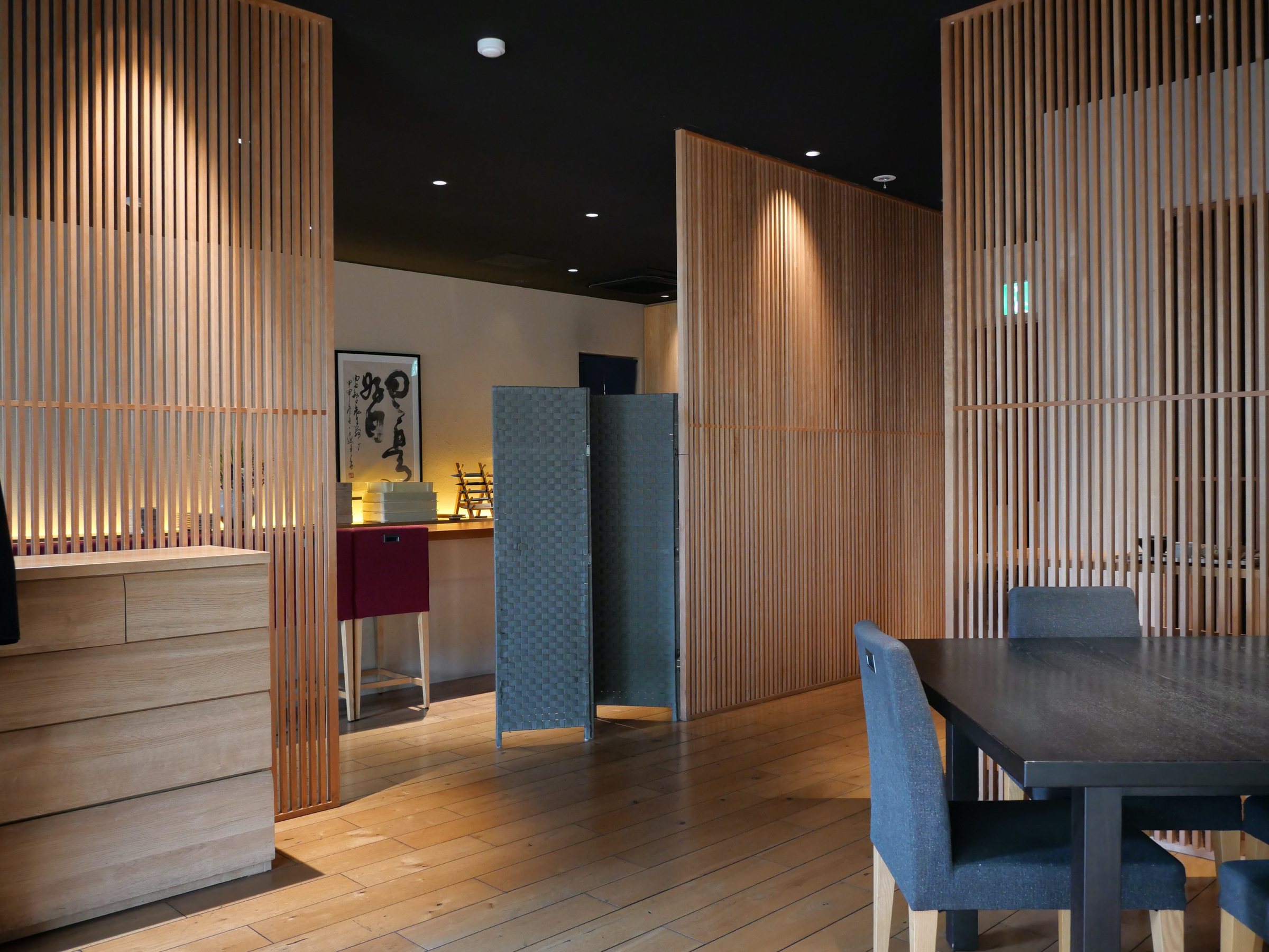 The dining room by day: pale timber slats and blue chairs.