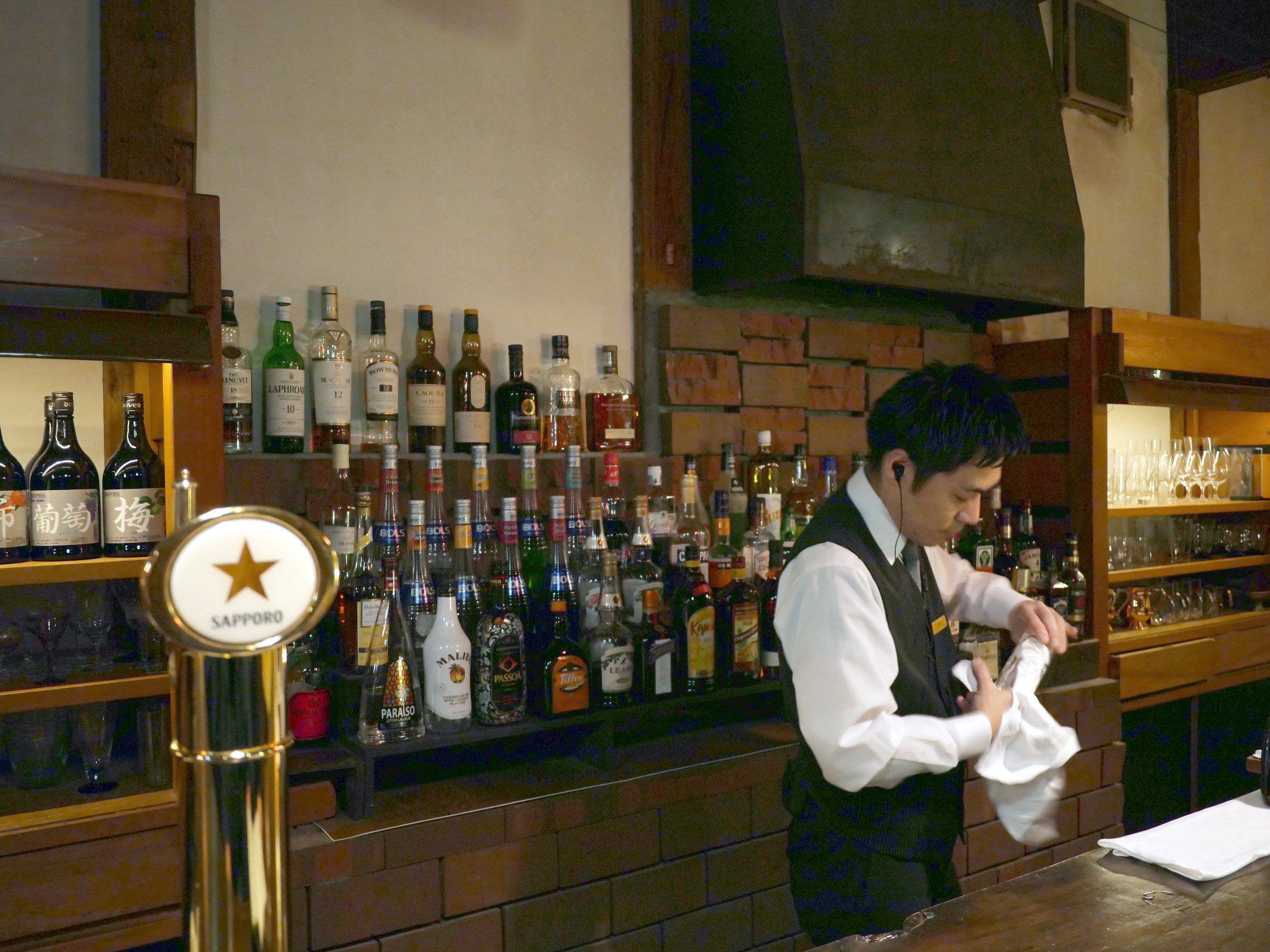 The bartender at work in front of shelves of bottles.