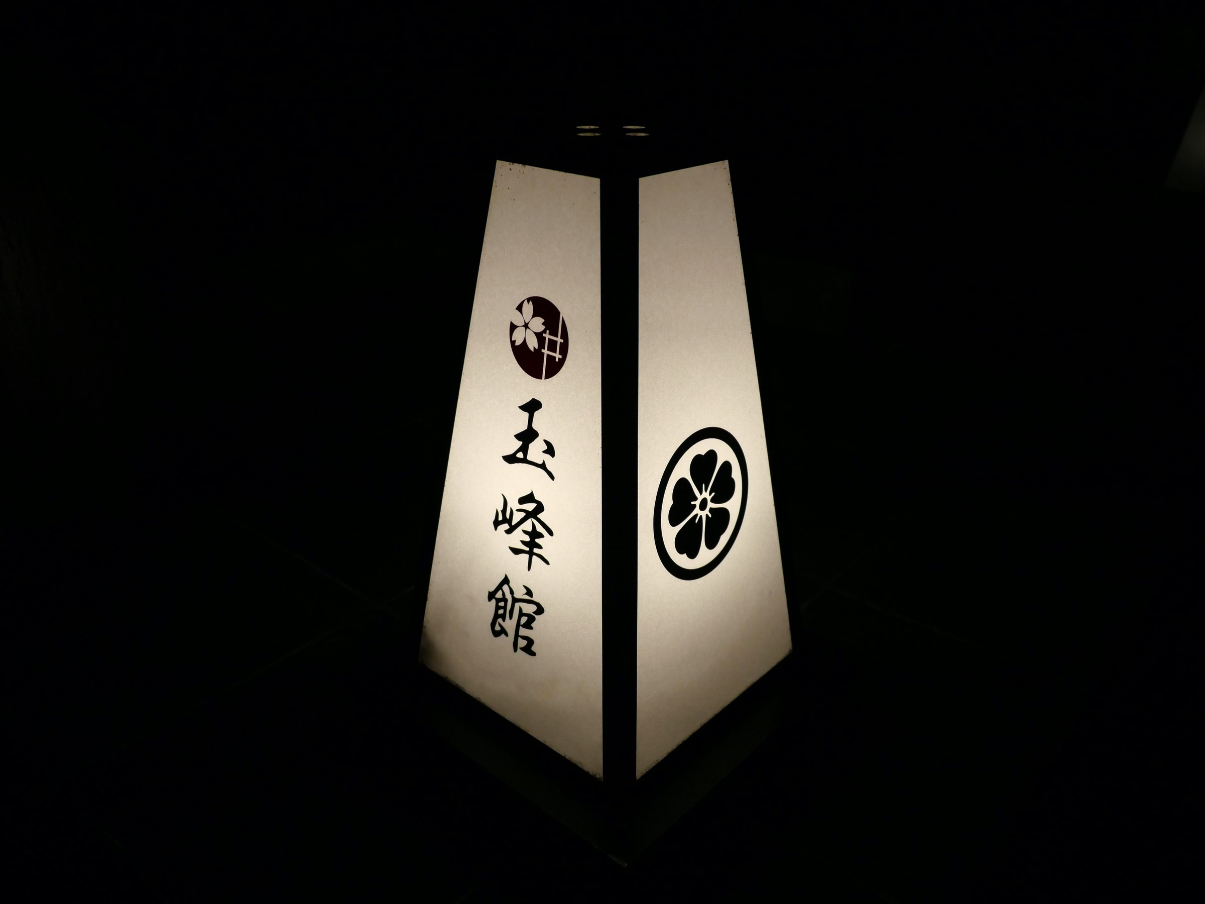 A lantern bearing the ryokan's name, glowing in the dark.