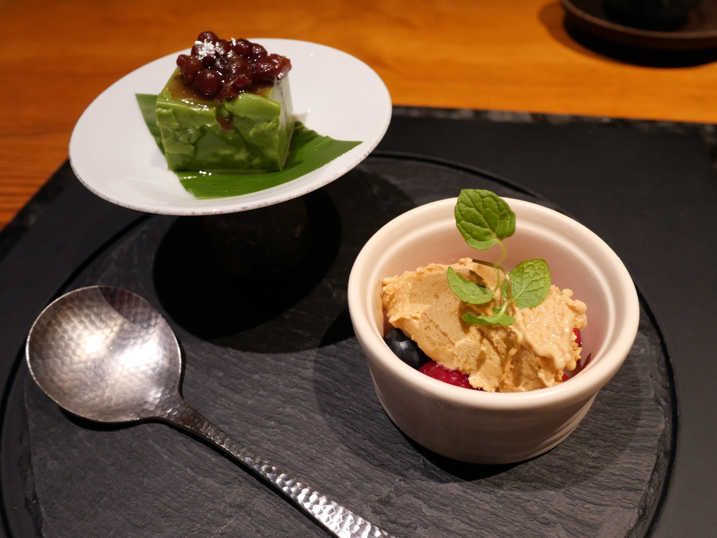 Dessert: a green pudding topped with sweet beans, and a small ramekin of cream.