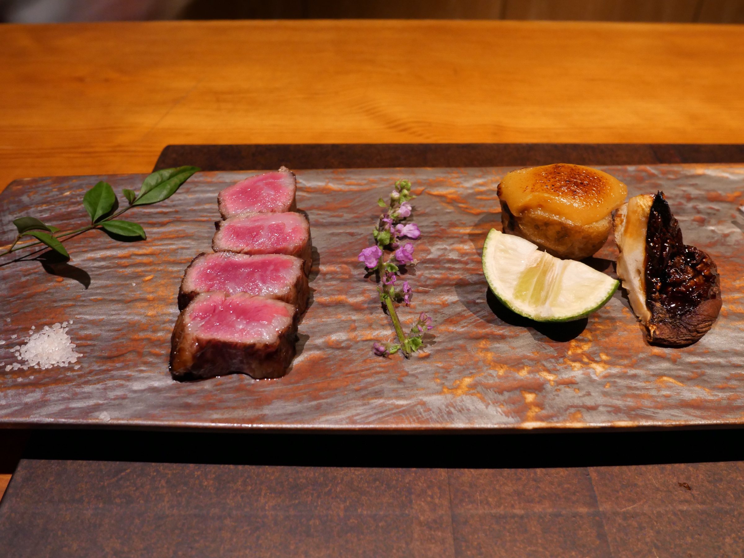 Slices of Wagyu sirloin with salt and a wedge of citrus.