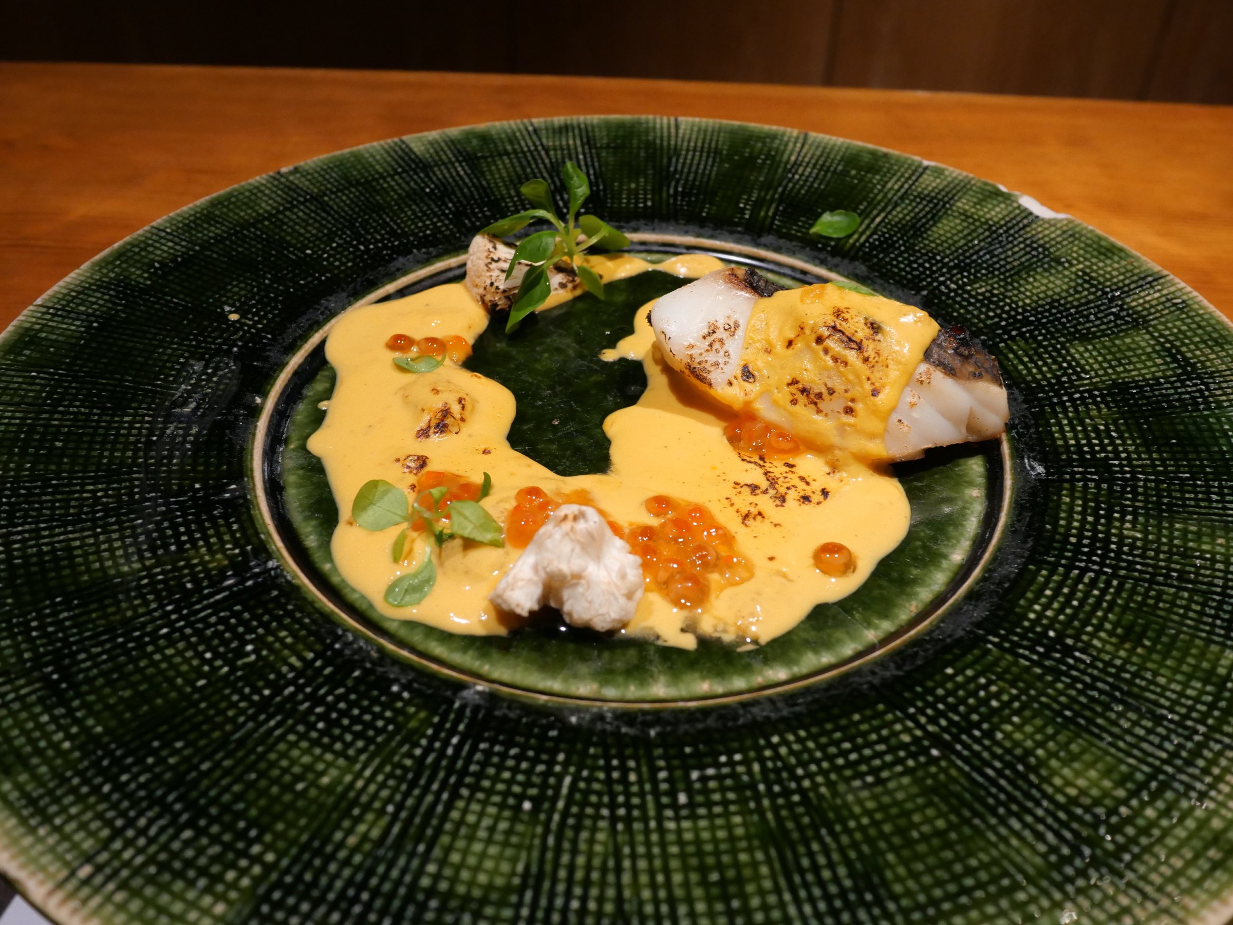 Kinmedai with a golden sauce on a green ceramic plate.