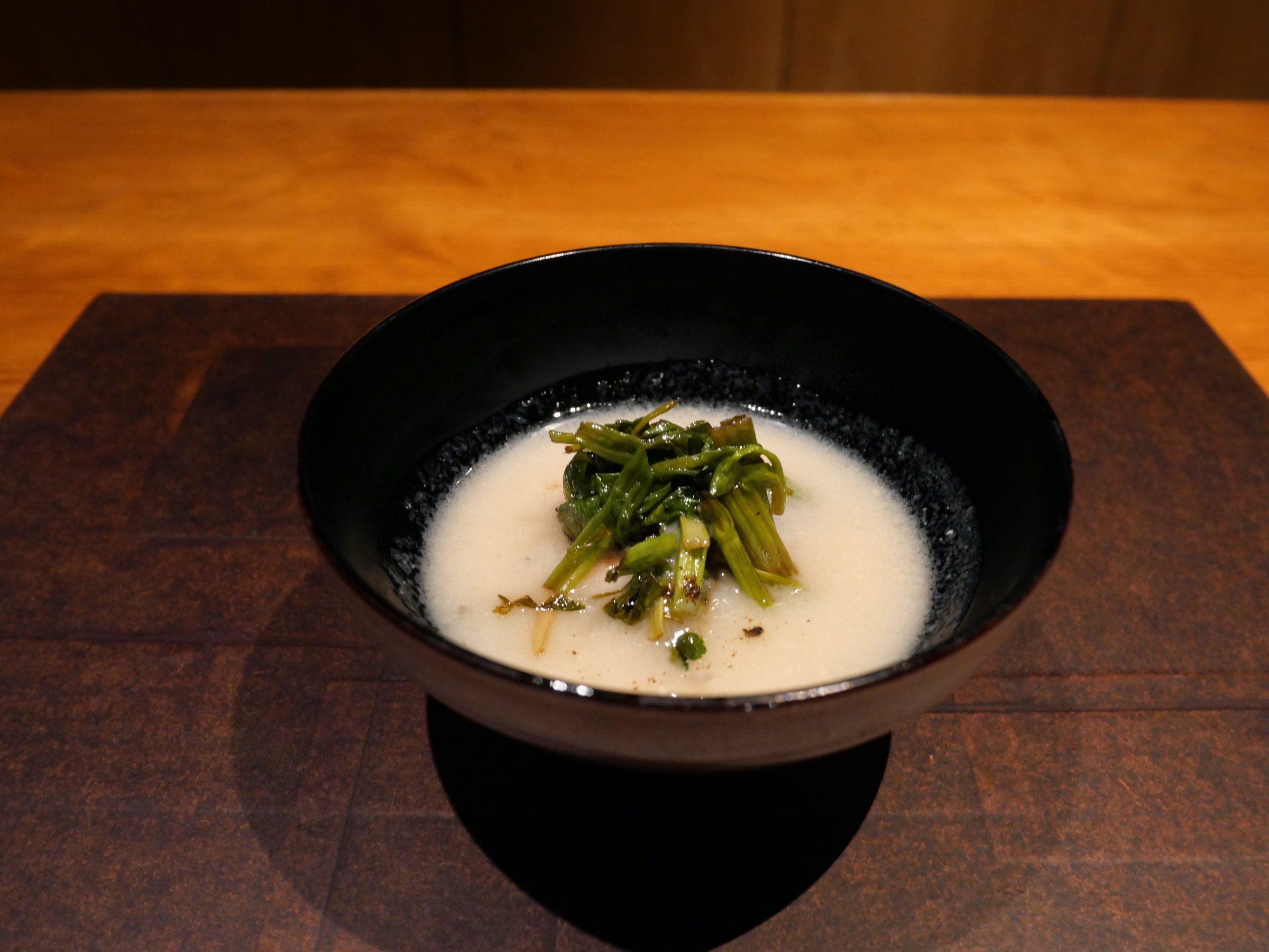 The soup revealed: a pale, creamy broth crowned with greens.