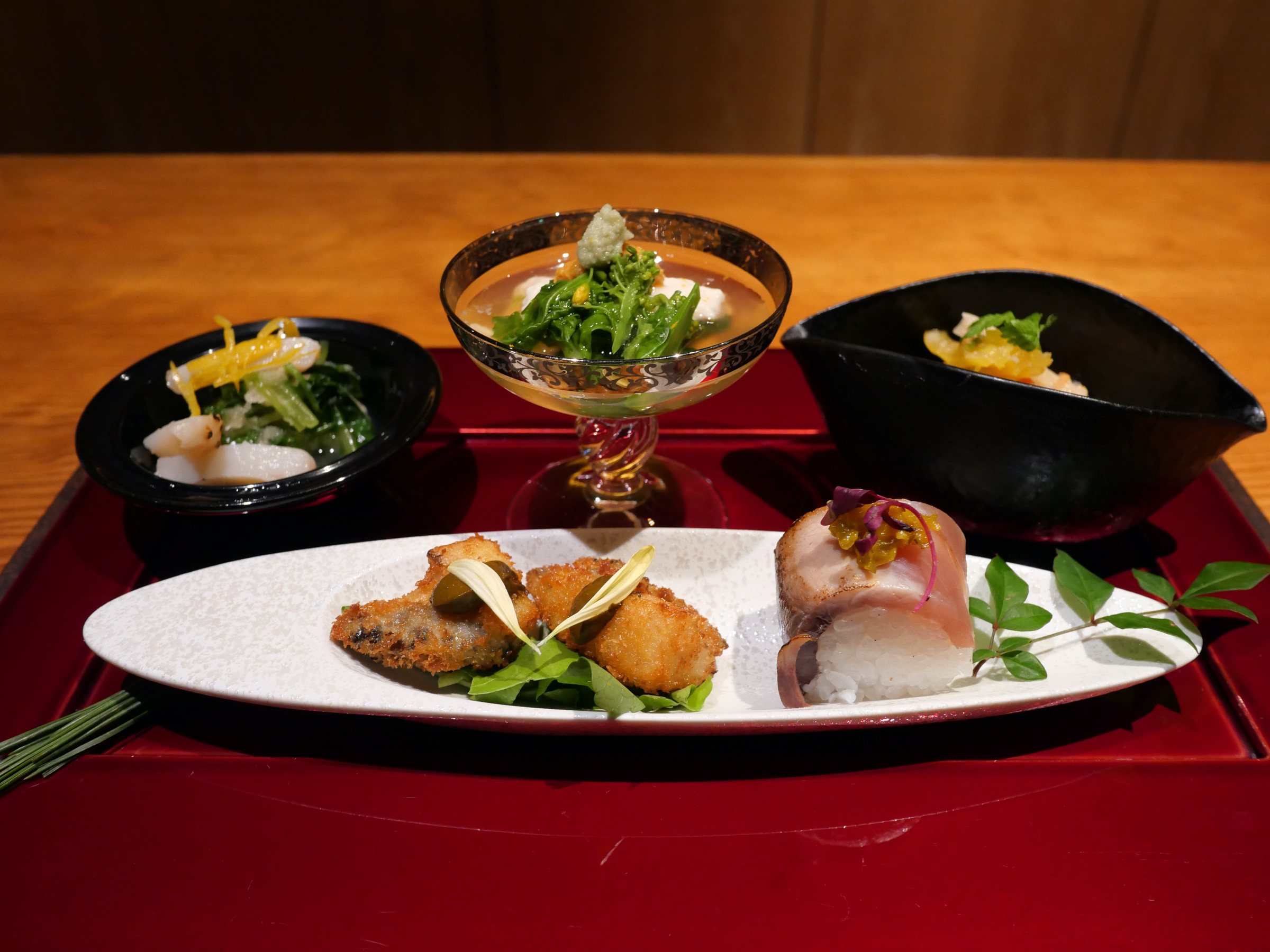 The appetisers on a red lacquer tray.