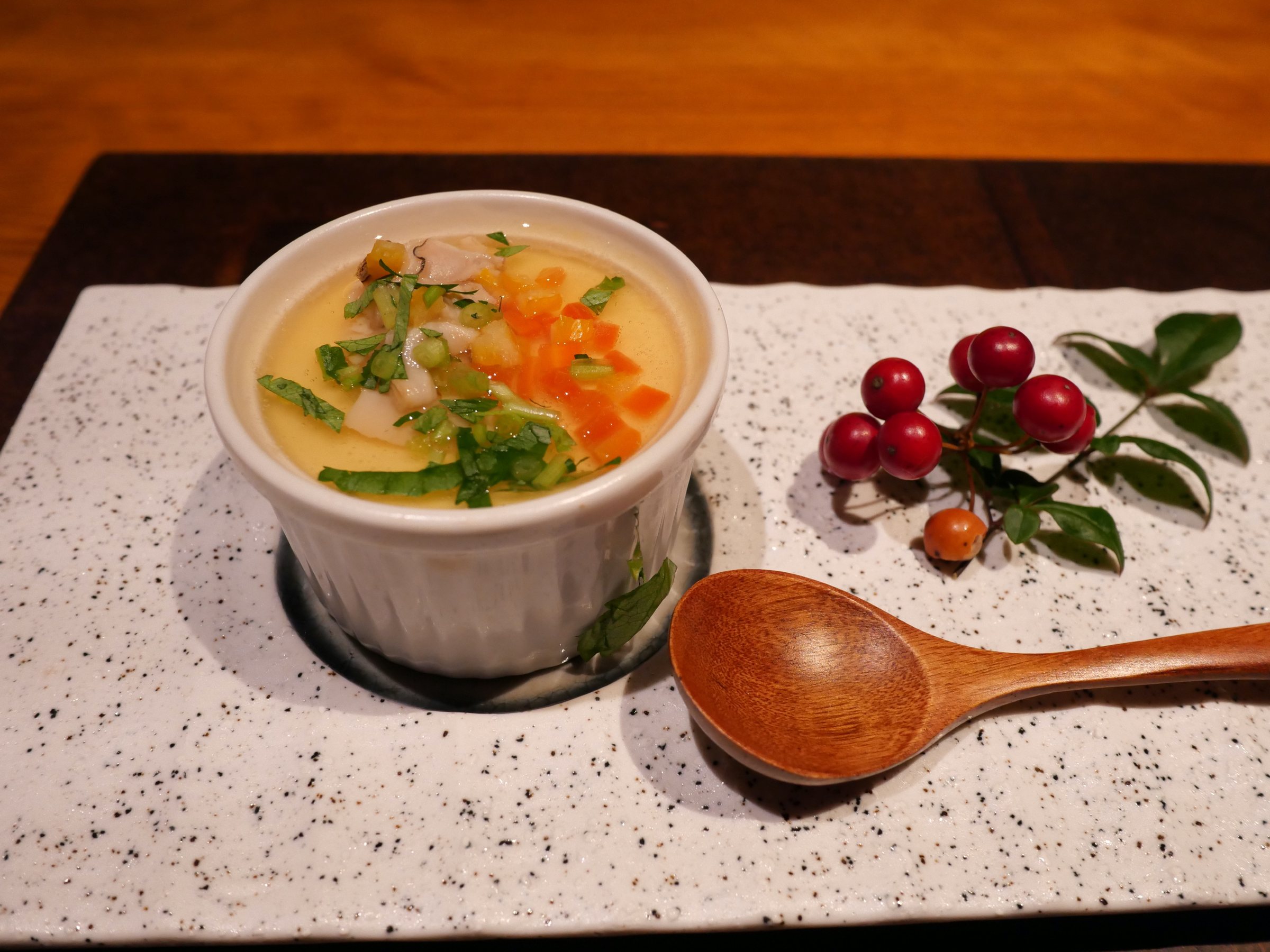 Clam chawanmushi, with a wooden spoon and a sprig of red berries.