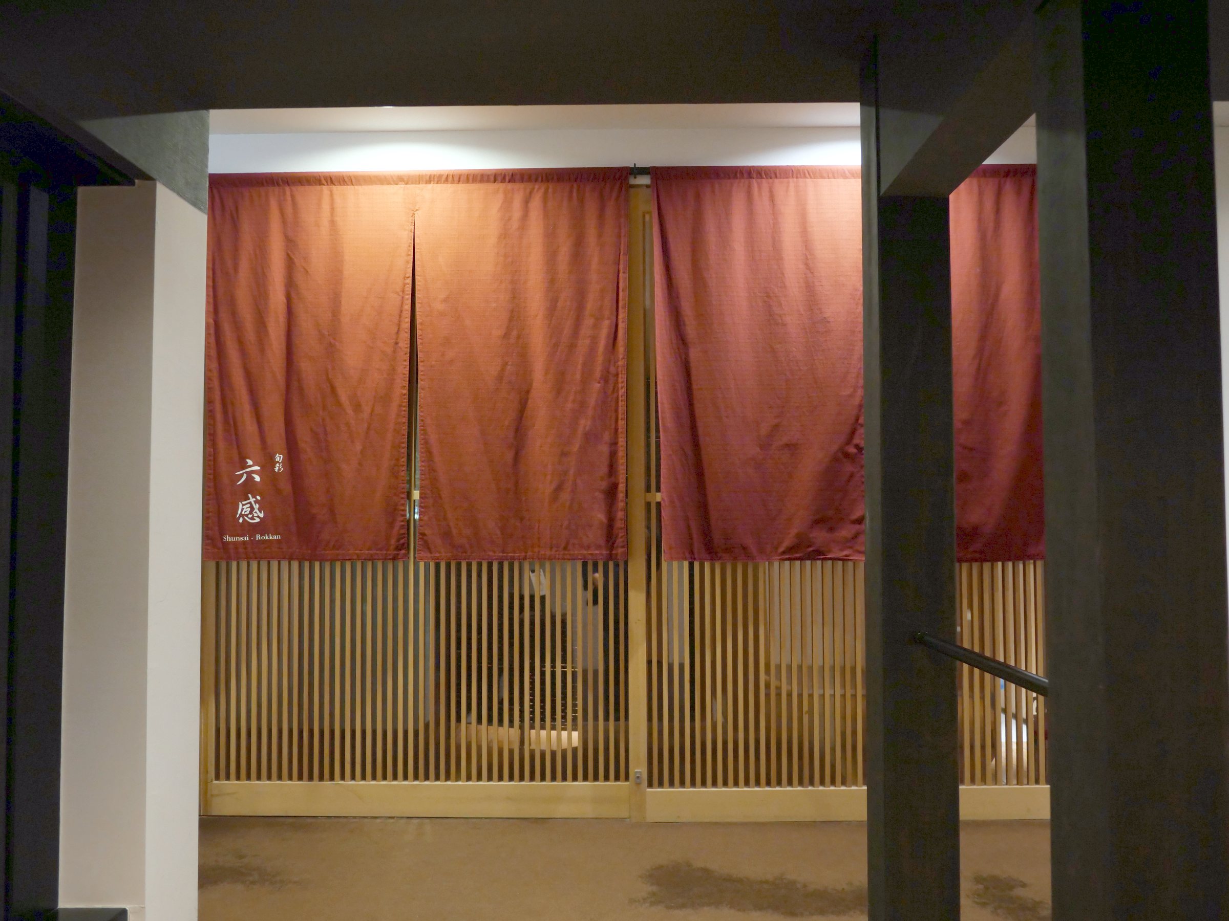 The dining room's entrance, hung with a deep red noren.