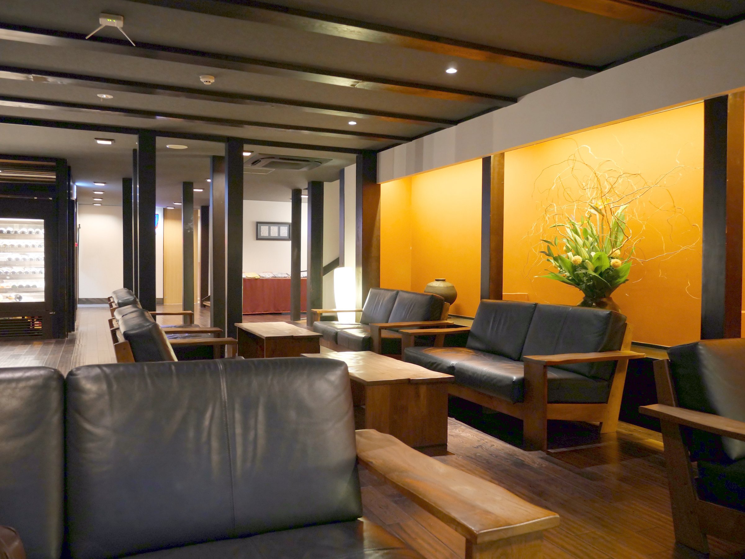 The lobby lounge: leather sofas, dark wood and a single arrangement against an orange wall.