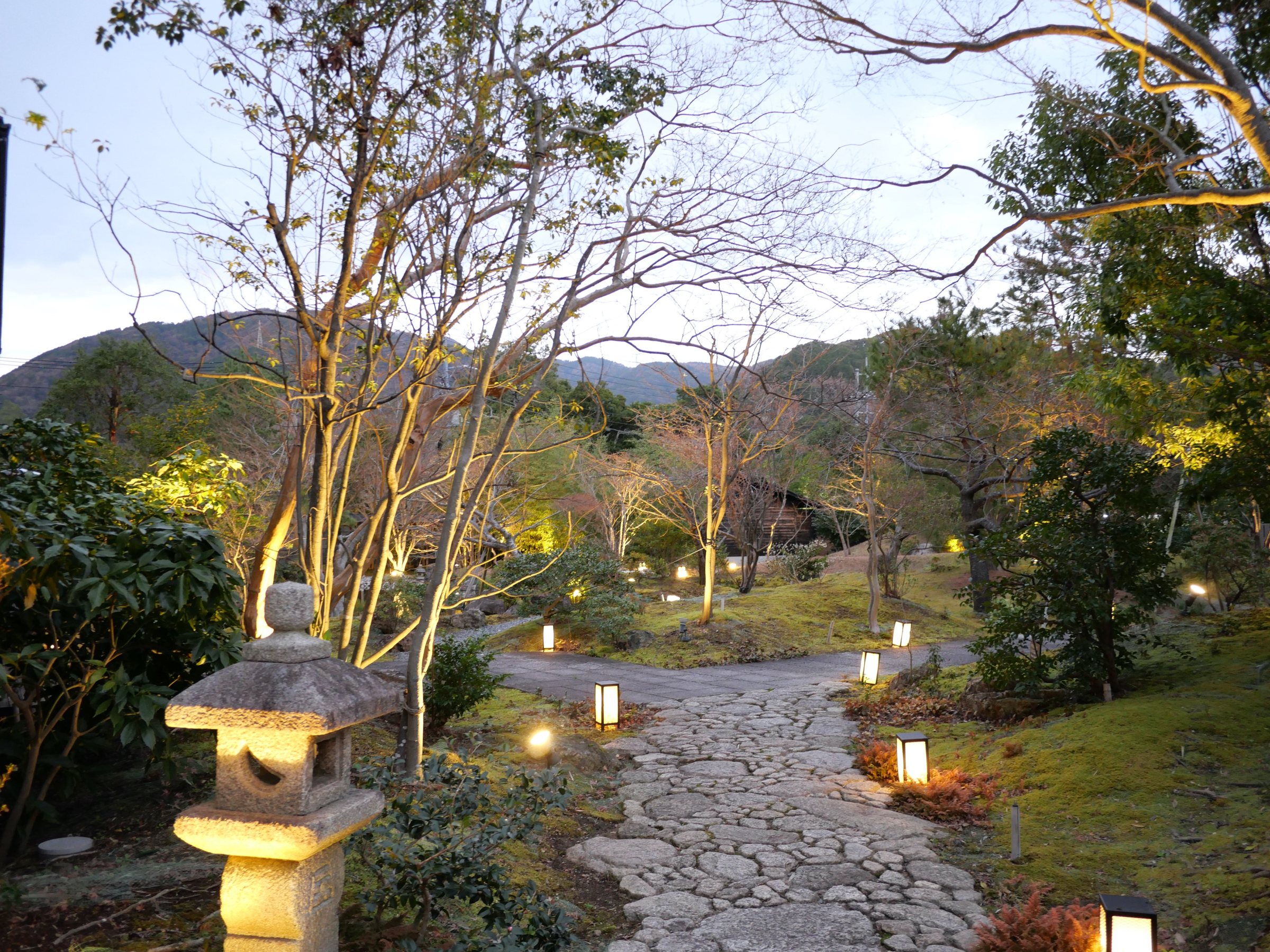 A stone lantern and a lit path through the evening garden.