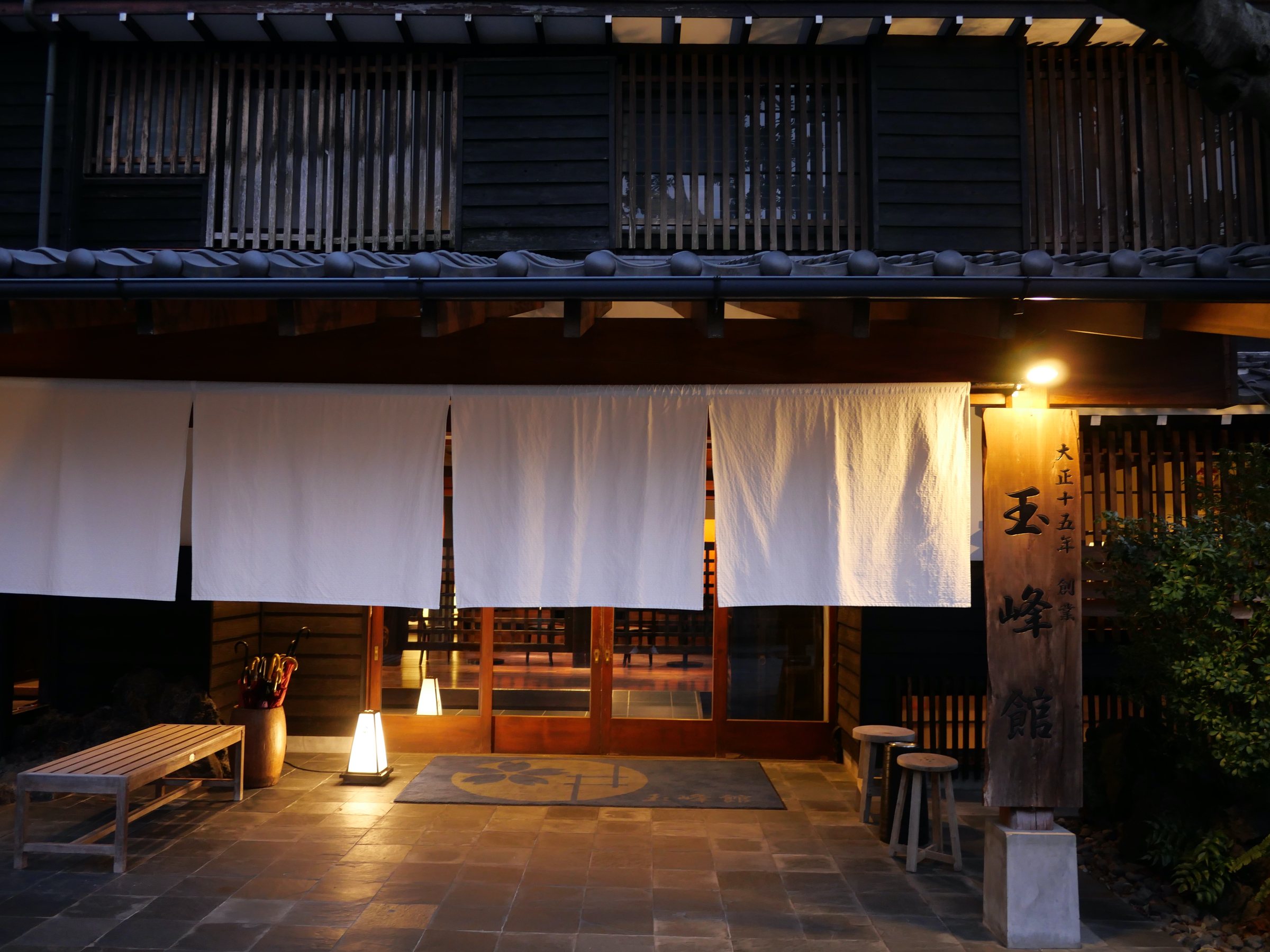 The entrance, hung with white noren and lit by a single lantern.
