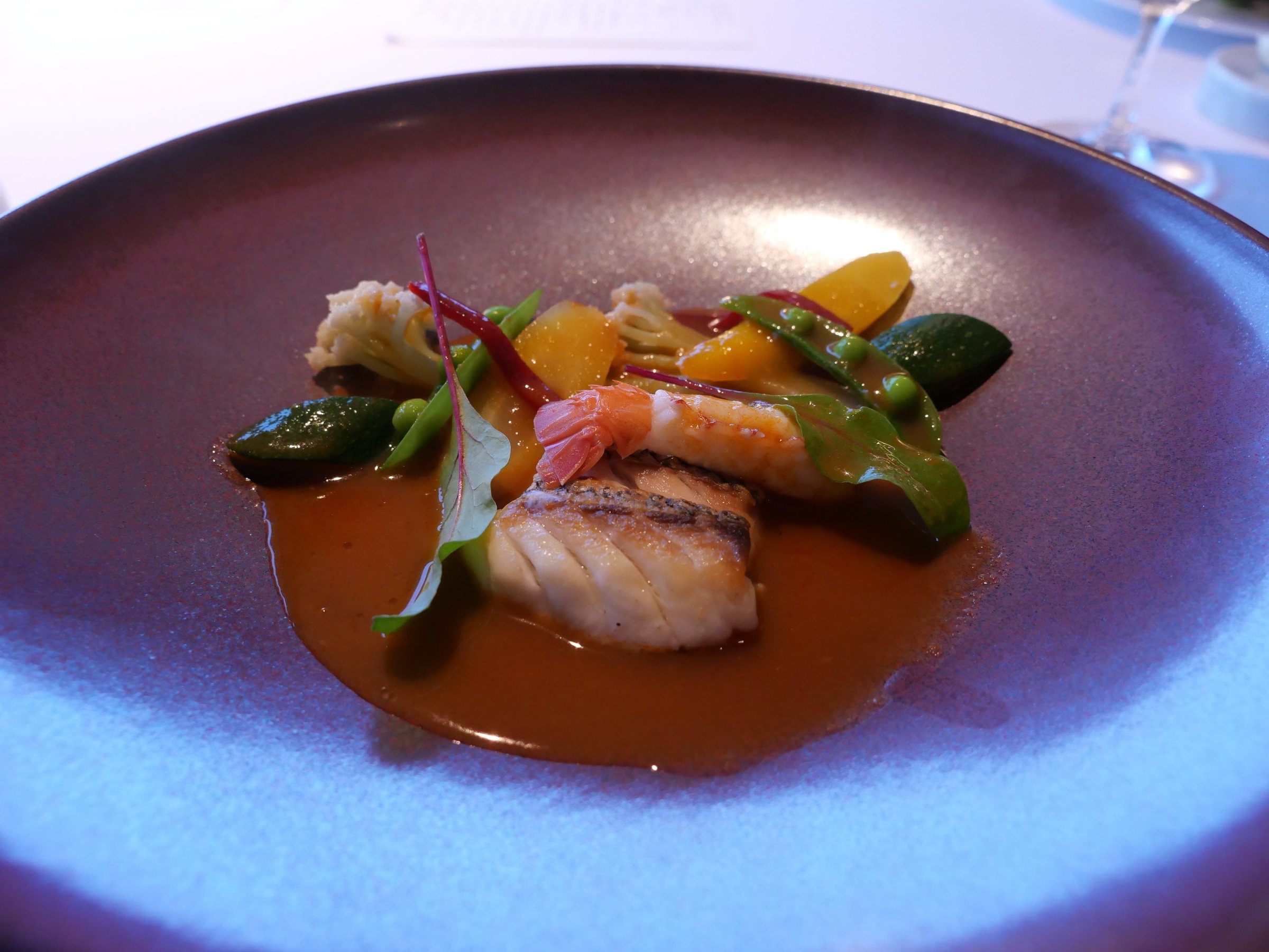The bouillabaisse-style fish and langoustine, in a deep violet dish.