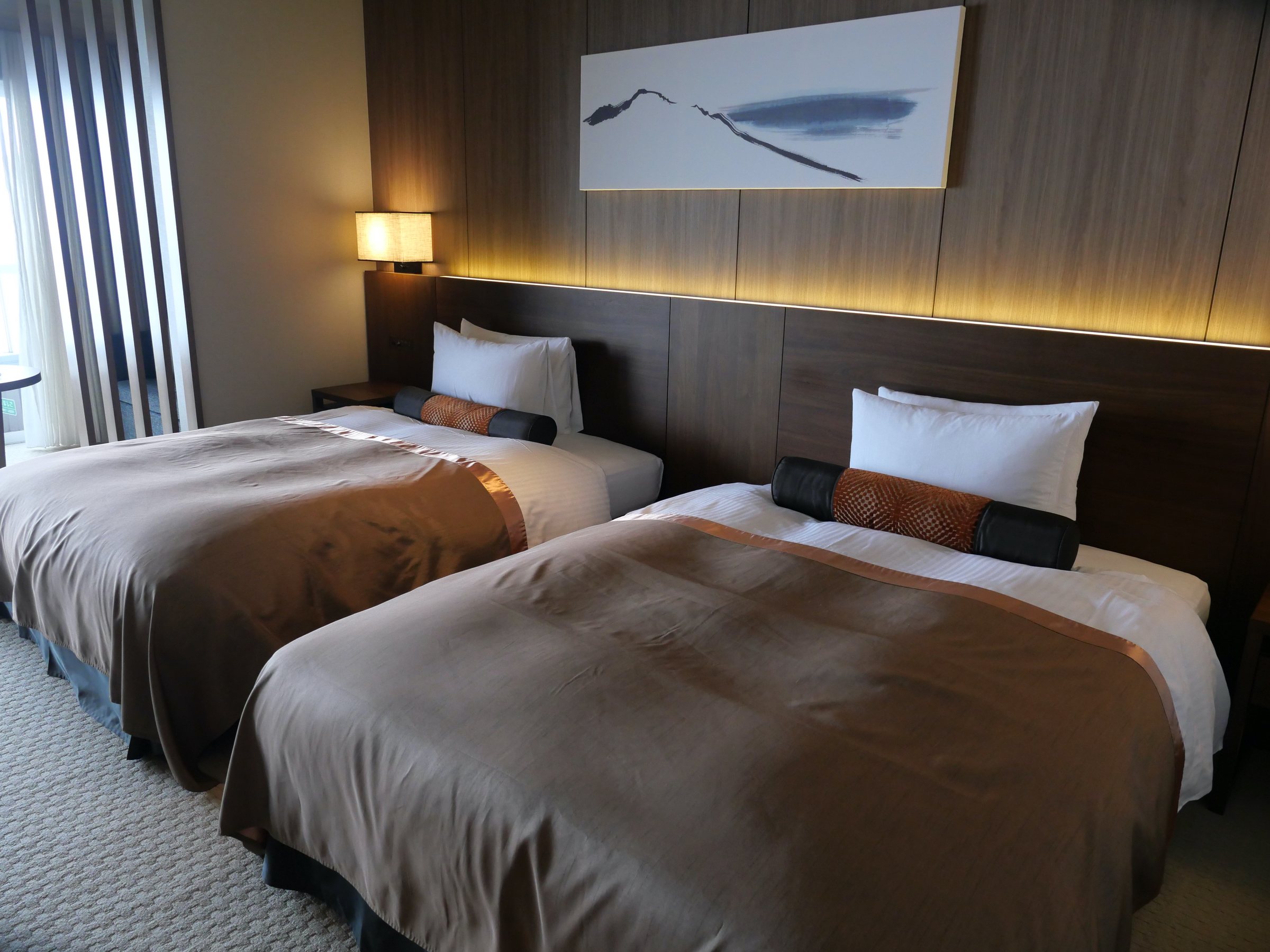 The bedroom: twin beds beneath a brushstroke artwork.