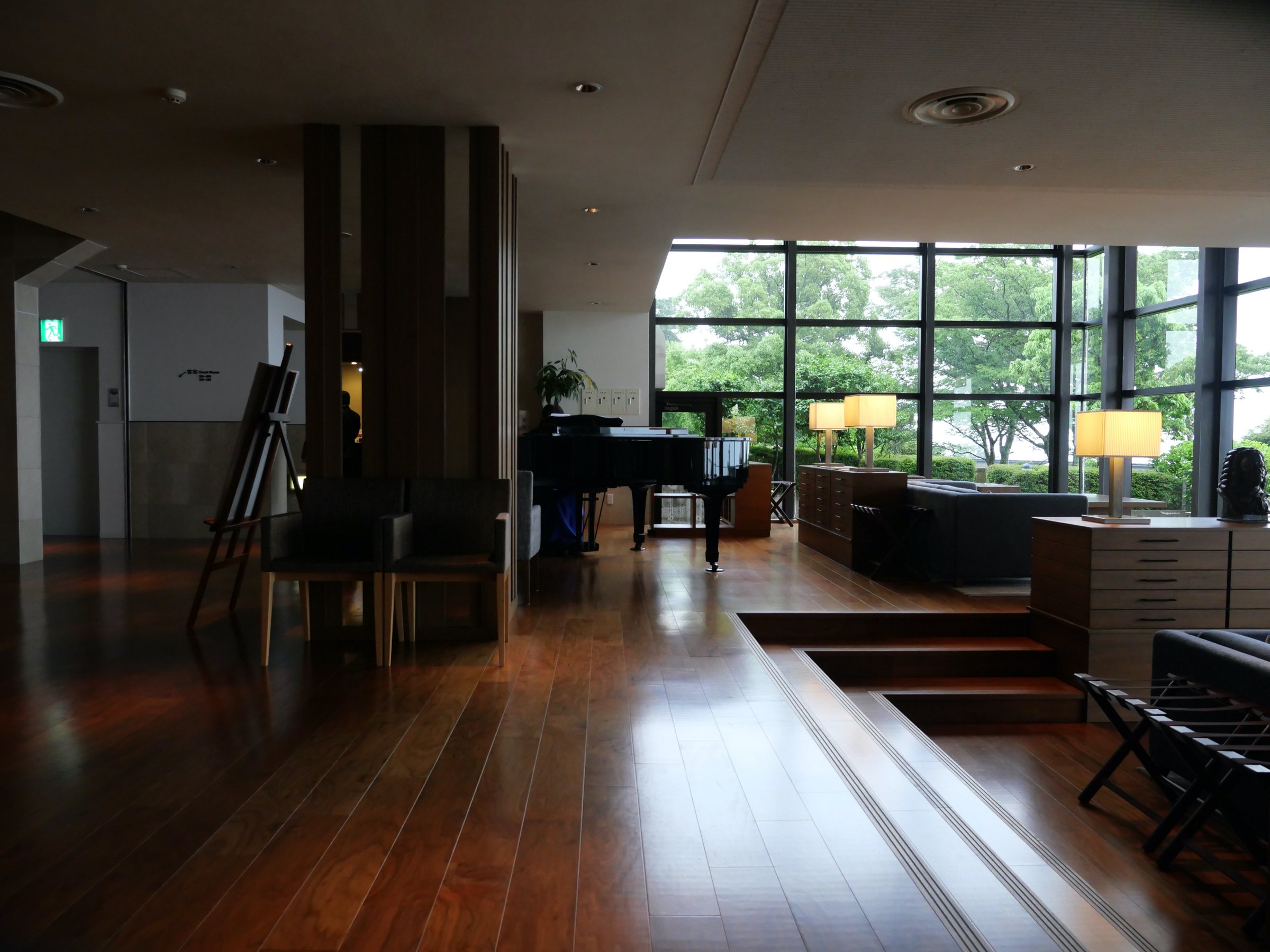 The lobby: polished timber floors, the grand piano and a wall of glass onto the greenery.