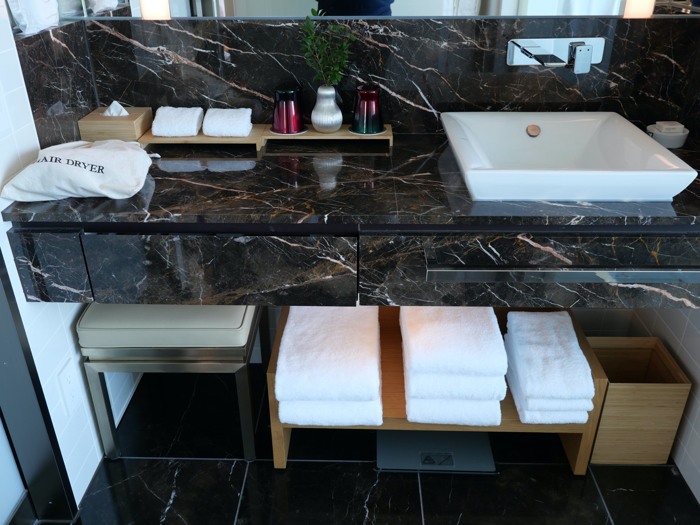 The vanity: dark marble, a white basin and stacks of towels.