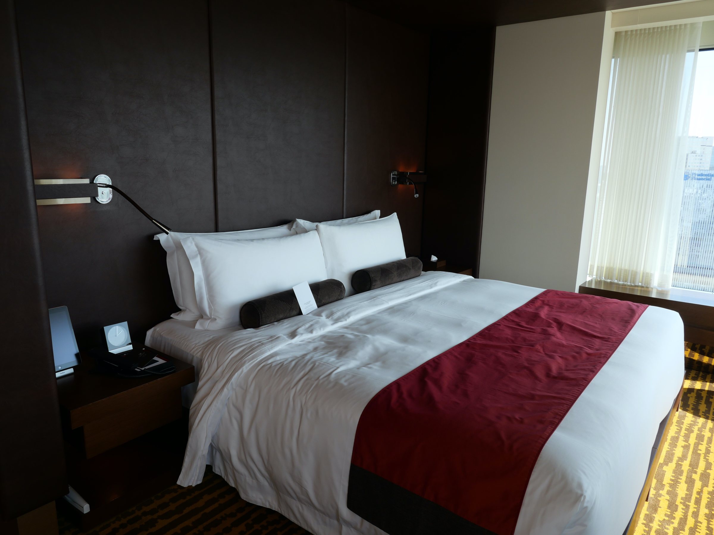 The bed, dressed in white and deep red.