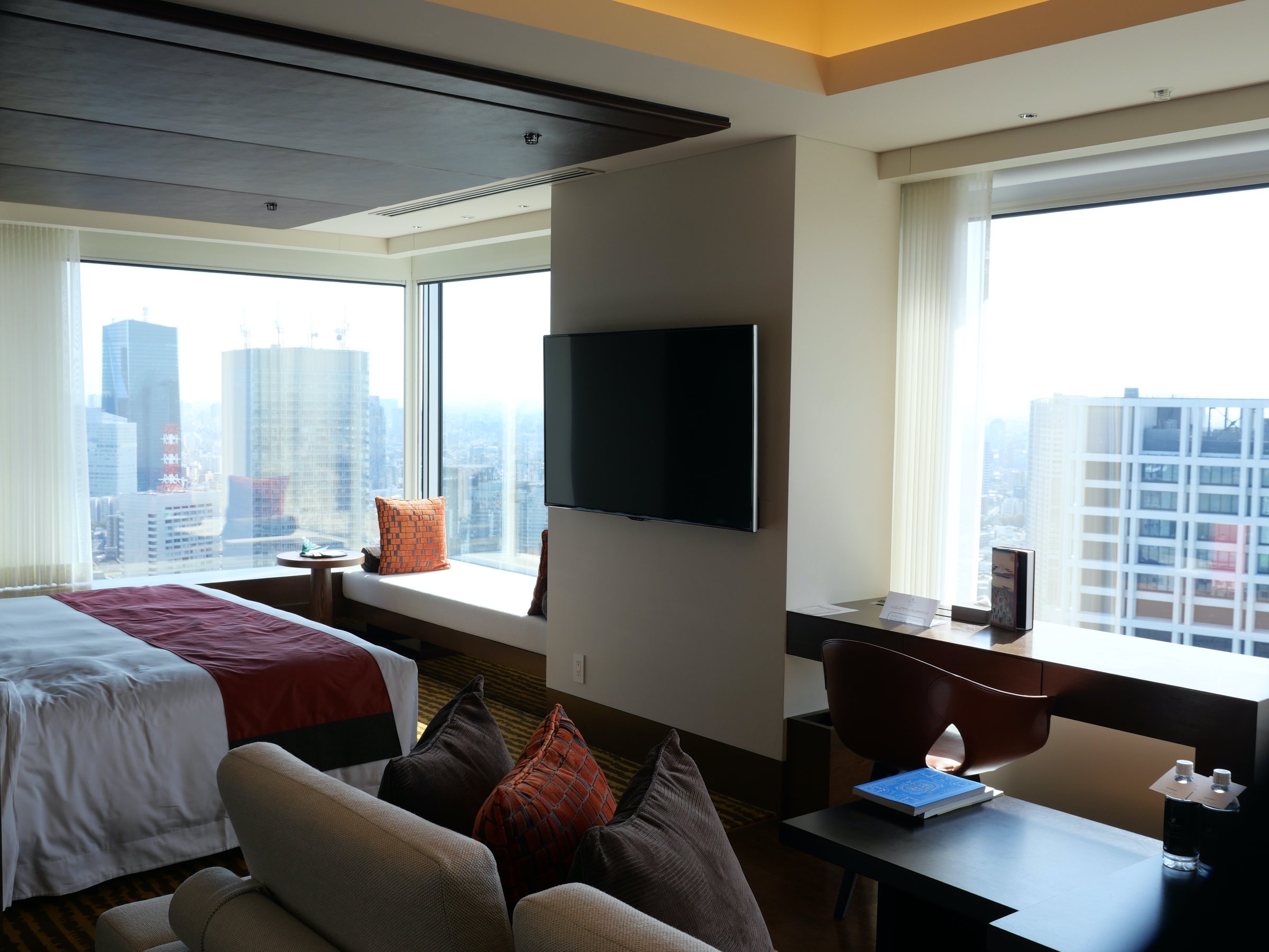 The room, wrapped in windows, with the city beyond.