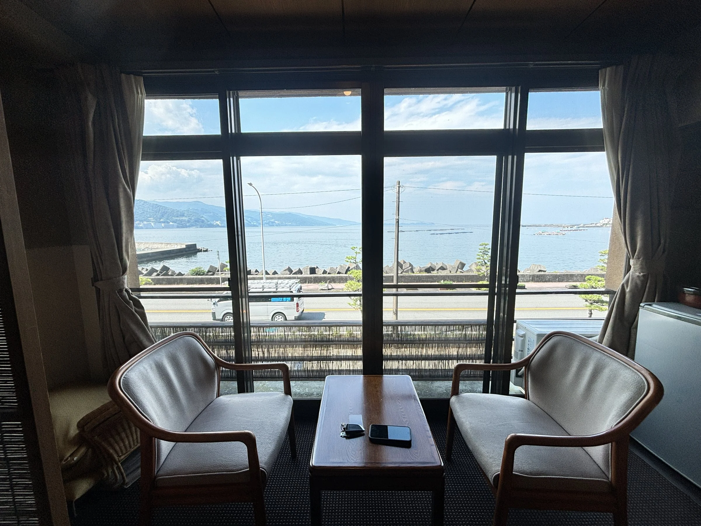 Two armchairs at the window, with the bay and the hills beyond.