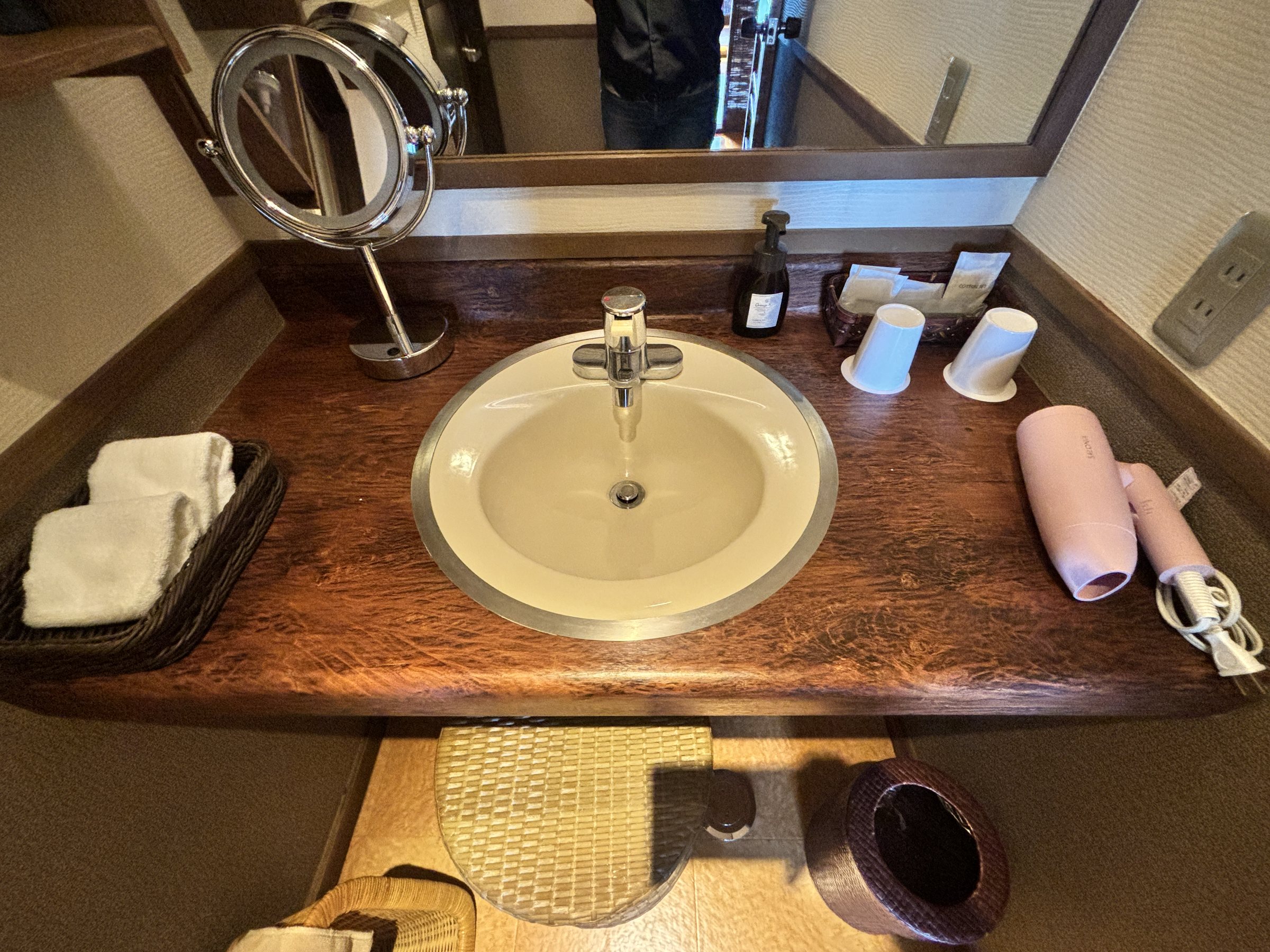 The washbasin on its wooden counter, with a magnifying mirror and hairdryer.