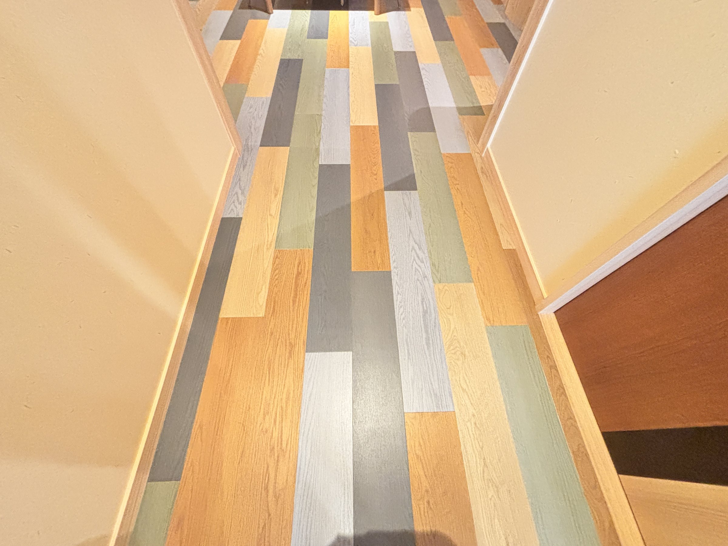 A corridor floored in soft, multicoloured boards.