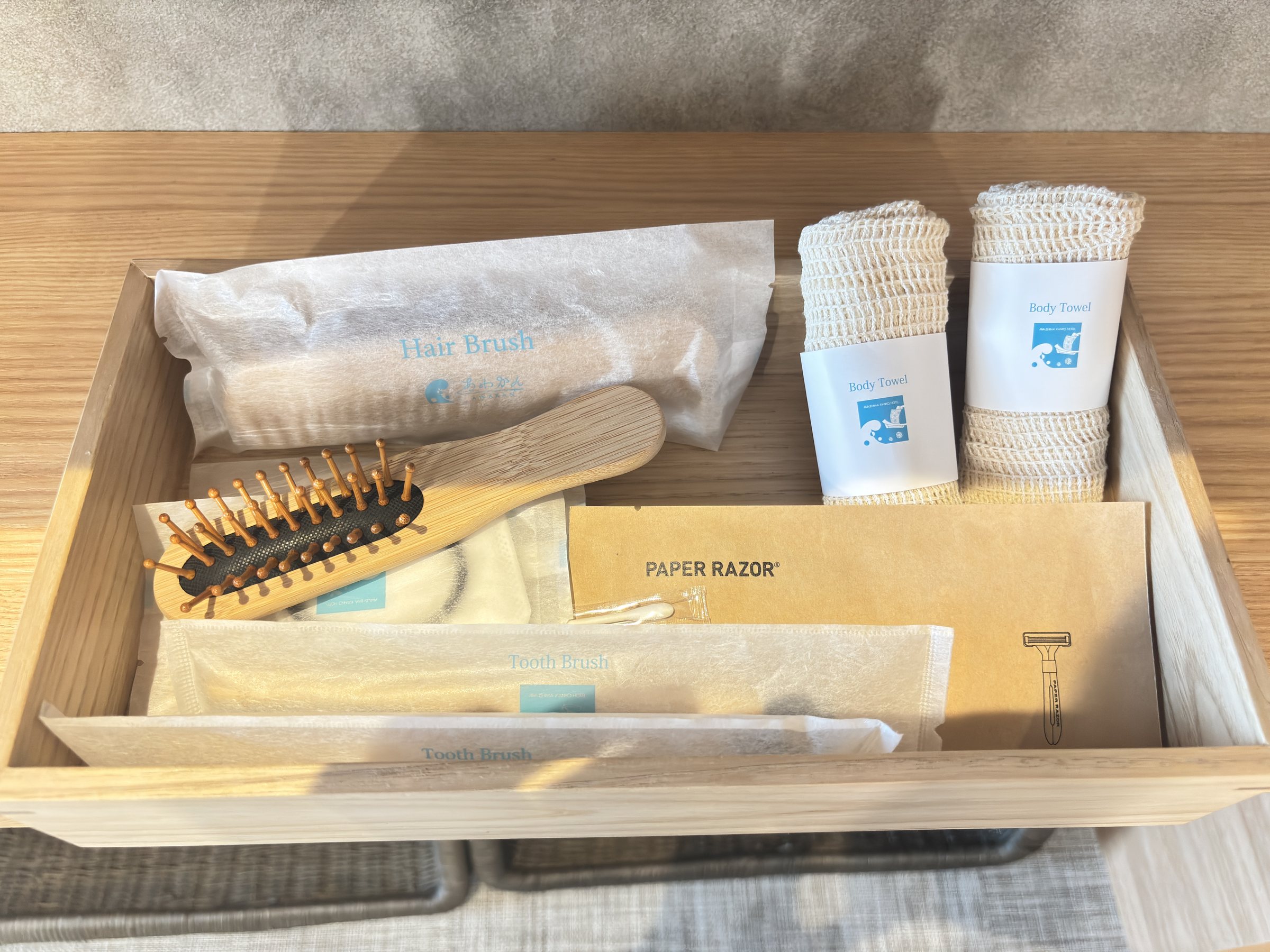 A wooden tray of amenities with the house logo.
