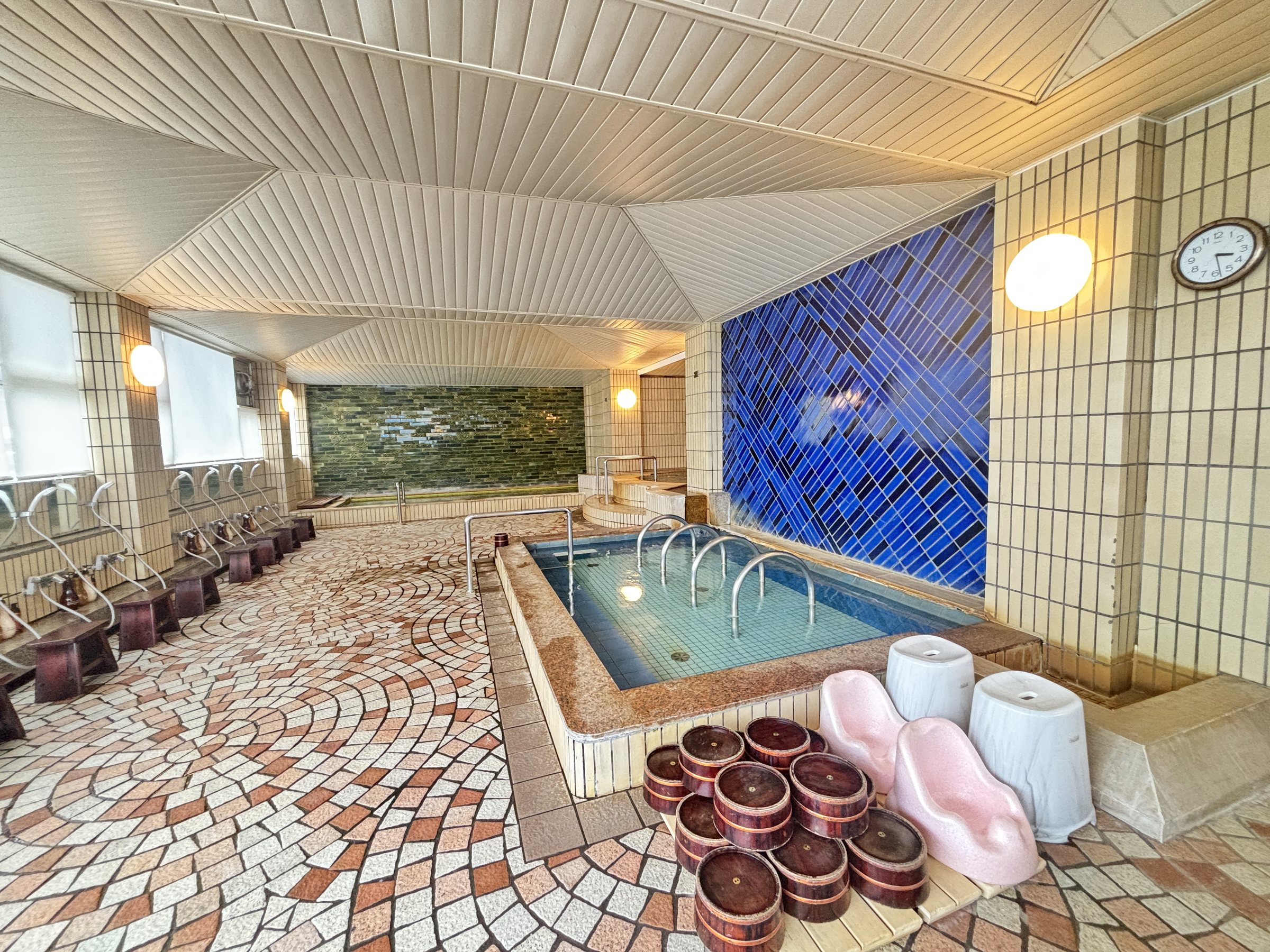 The main bath hall, with a blue tiled wall and mosaic floor.