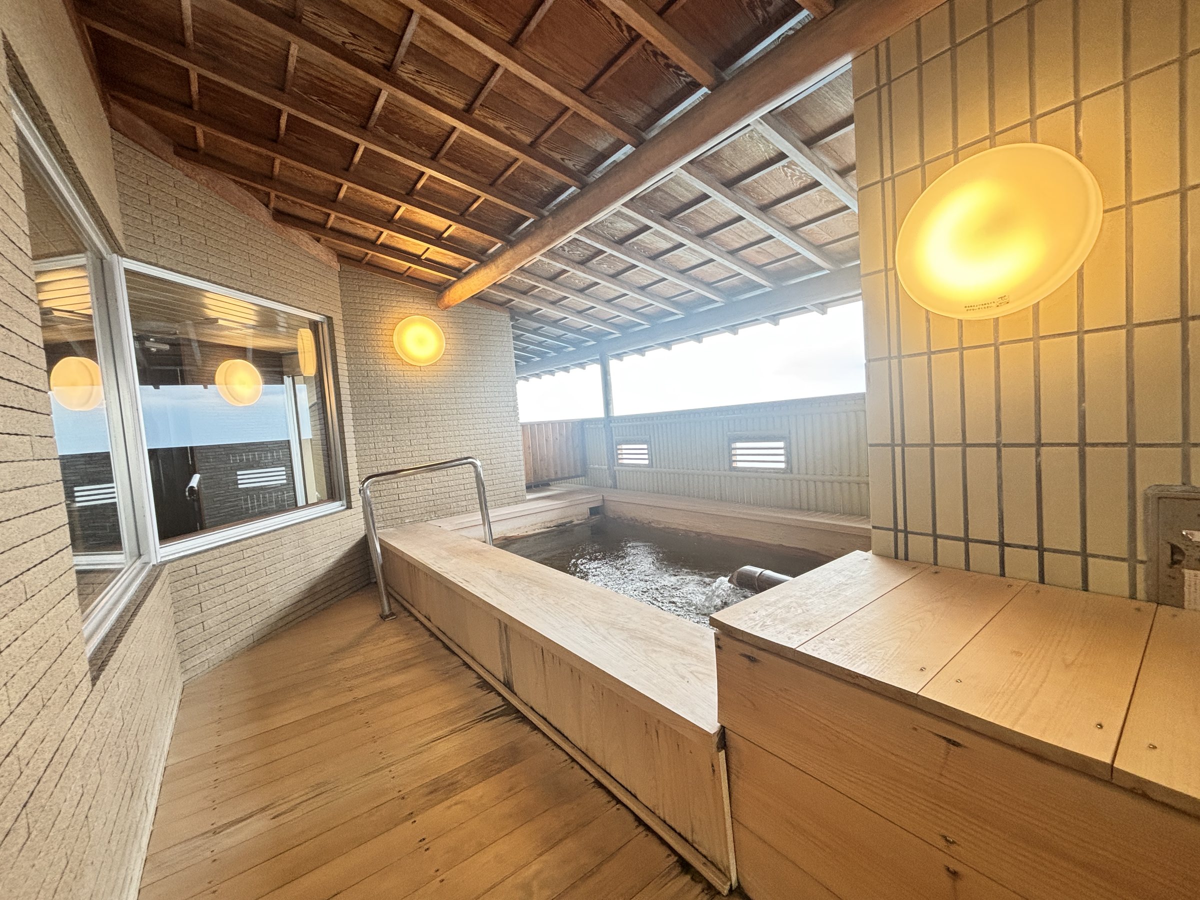 A wooden-edged bath under a coffered ceiling.