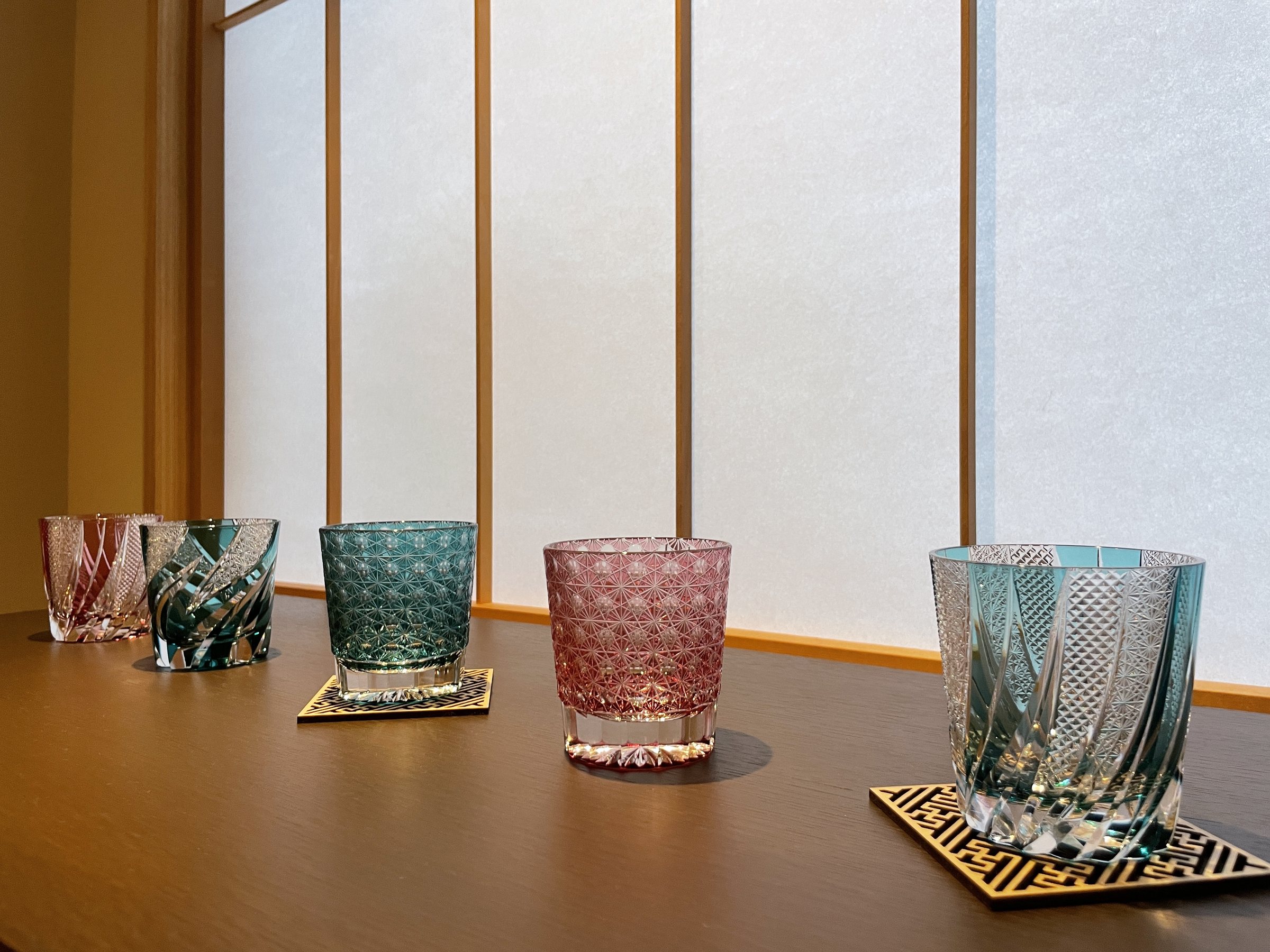 Cut-glass tumblers in red, green and blue lined up before white shoji.