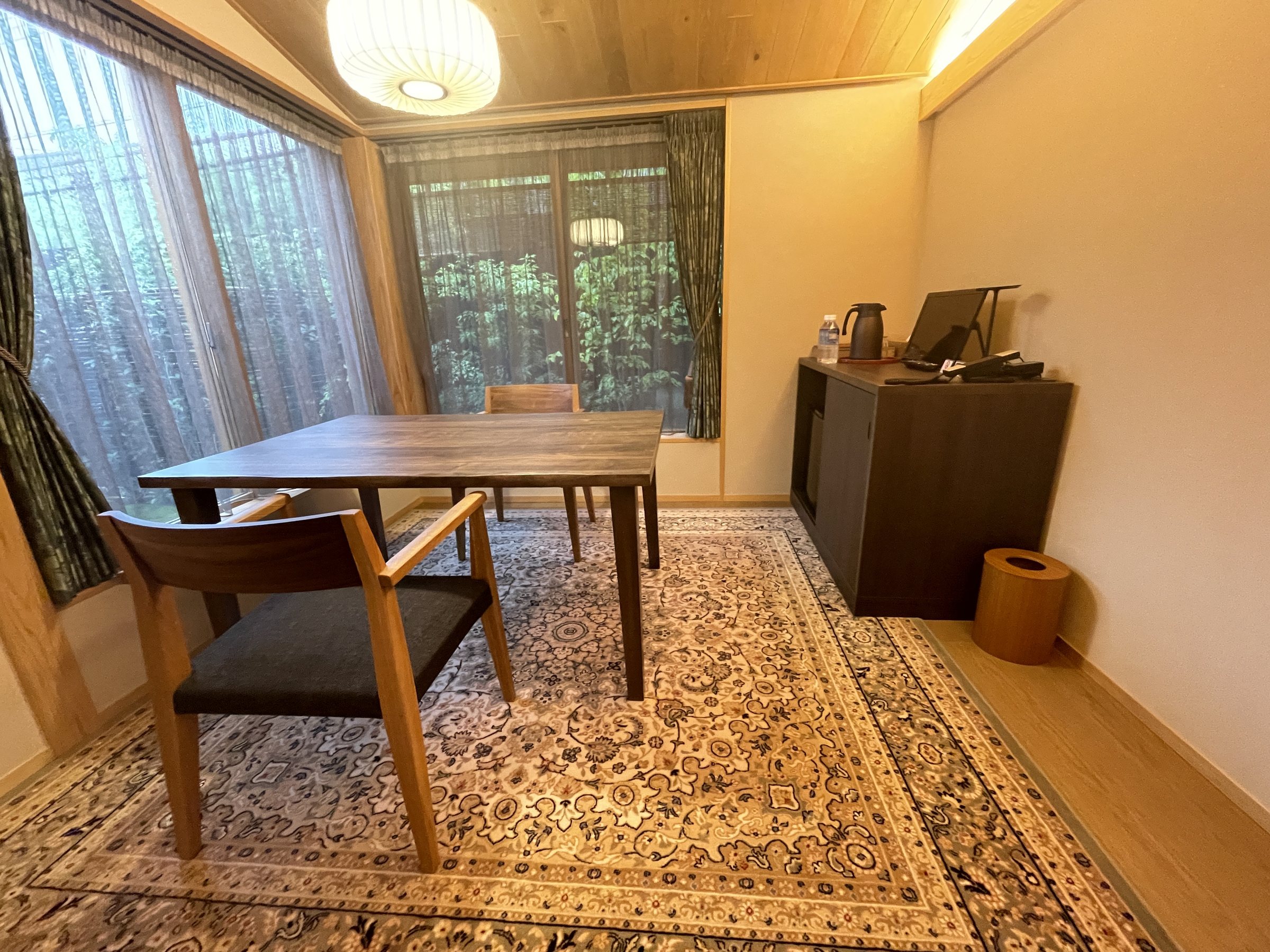 The dining room, with a wooden table and chairs on a patterned carpet.