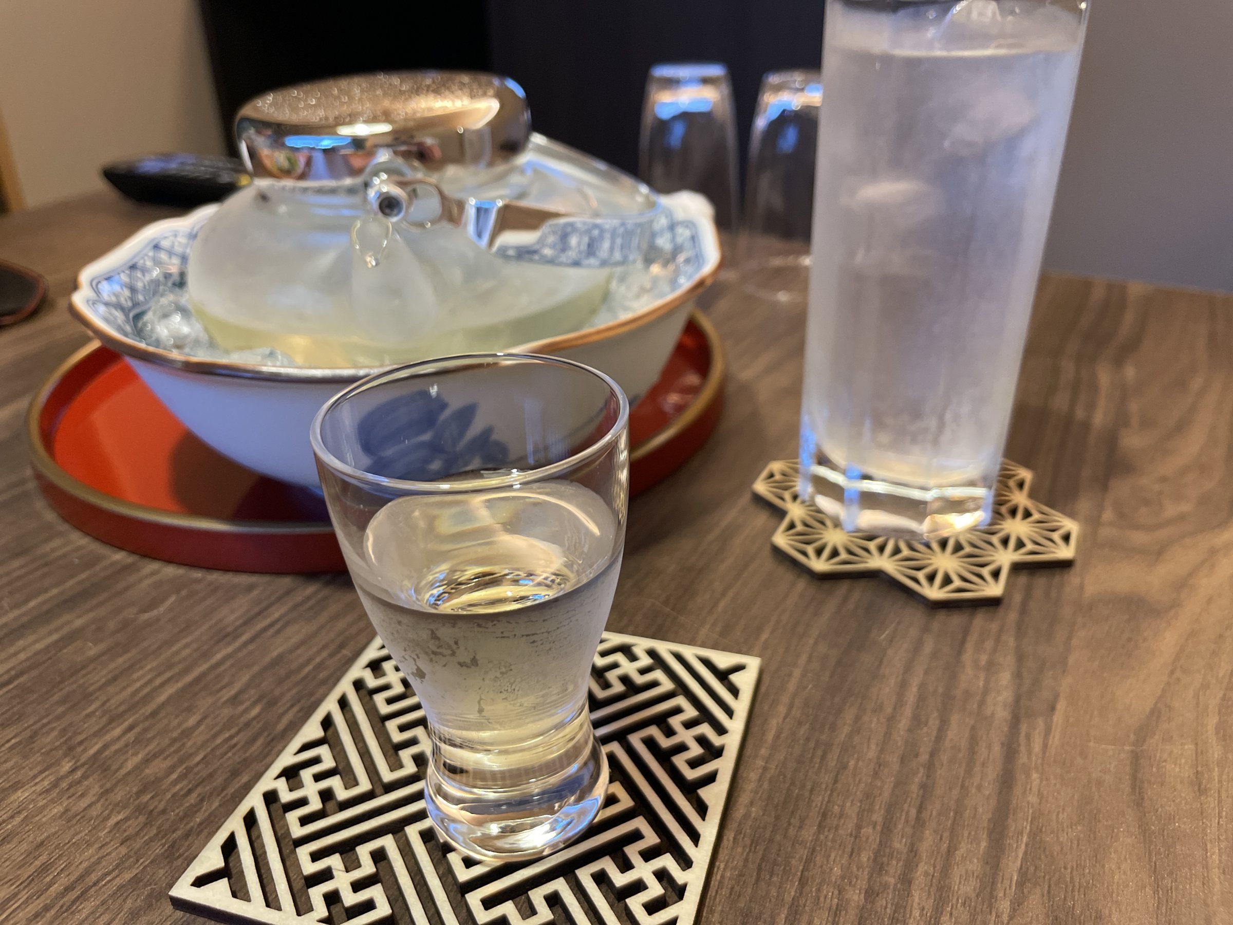 A glass of chilled sake beside a carafe on ice and a glass of water.