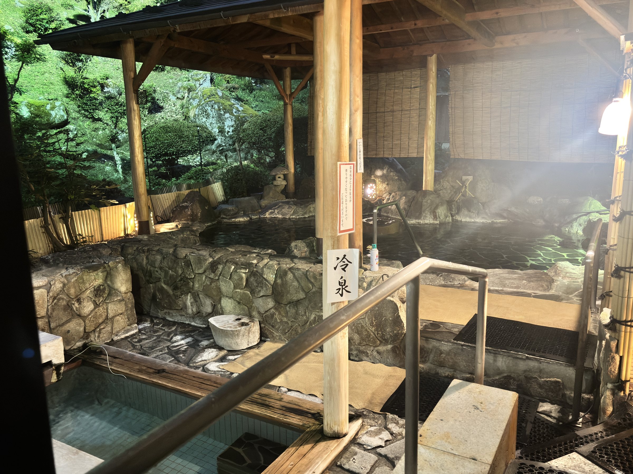 The open-air bath under a timber roof, with a sign marking the cold spring.