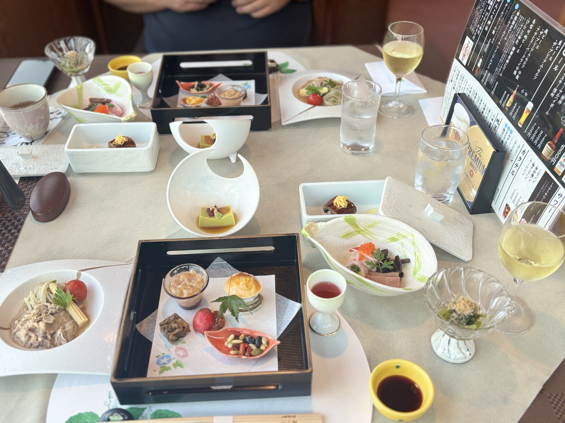 The table laid with the opening dishes and glasses of white wine.