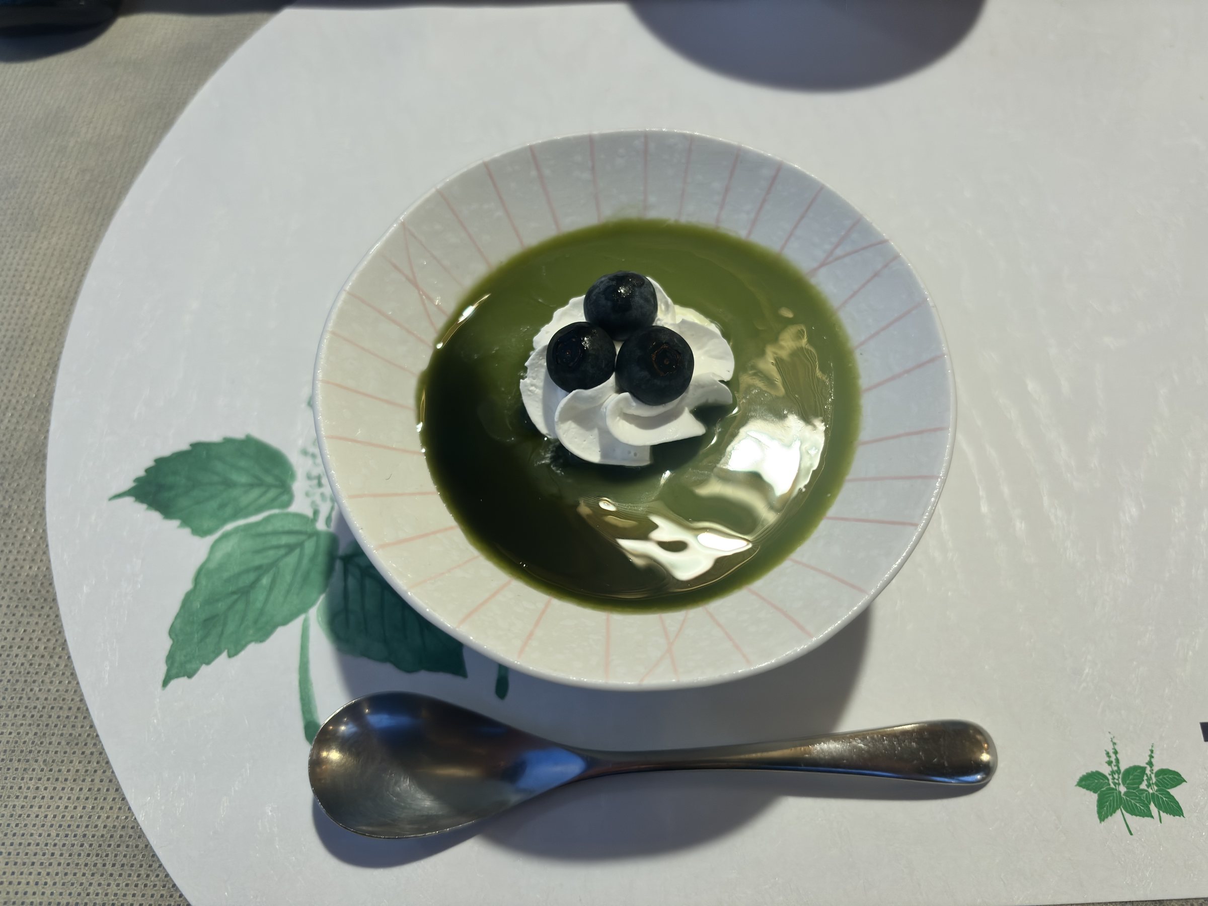Matcha pudding topped with cream and black beans.