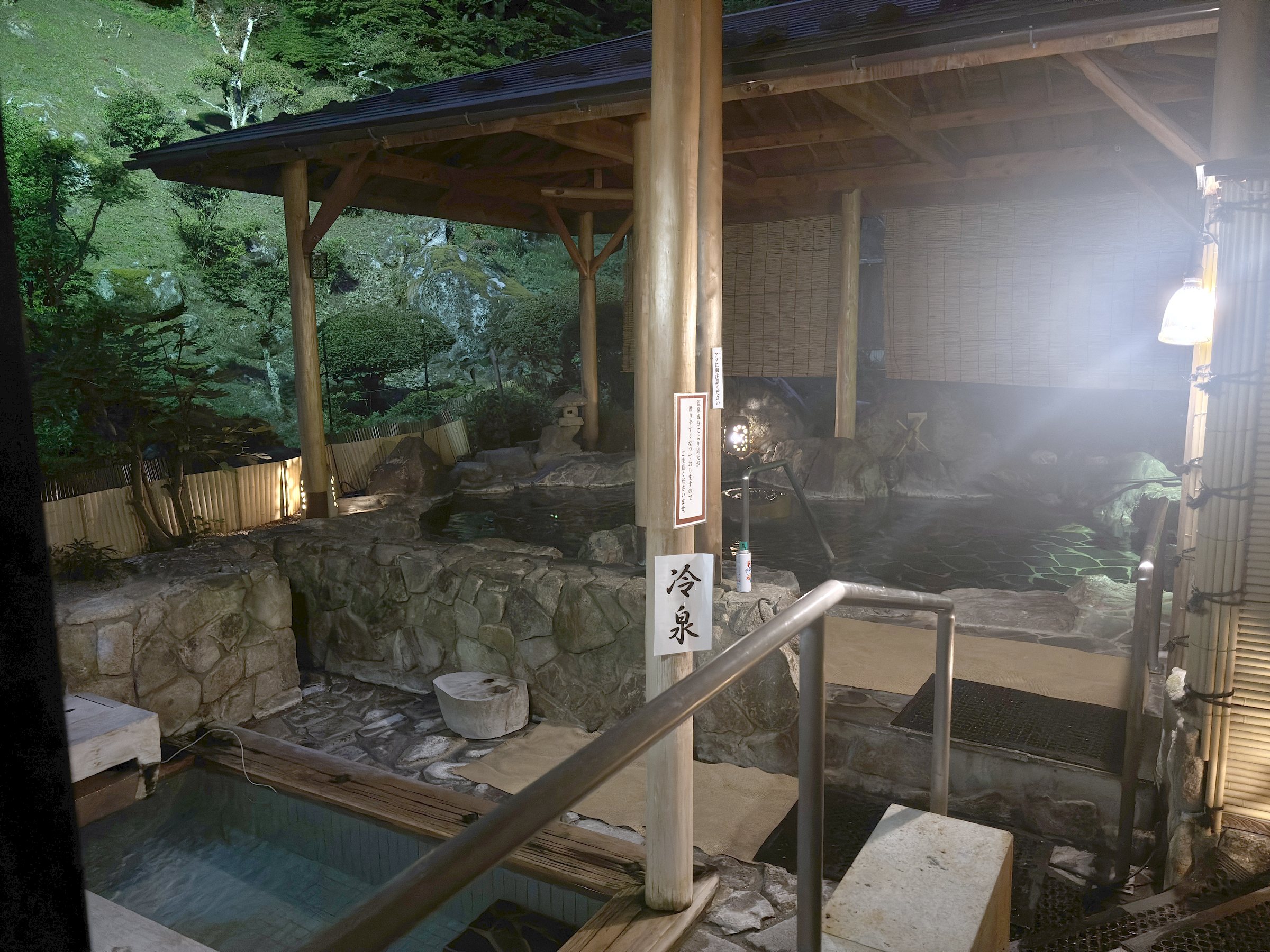 The open-air bath at night, lit by lanterns.
