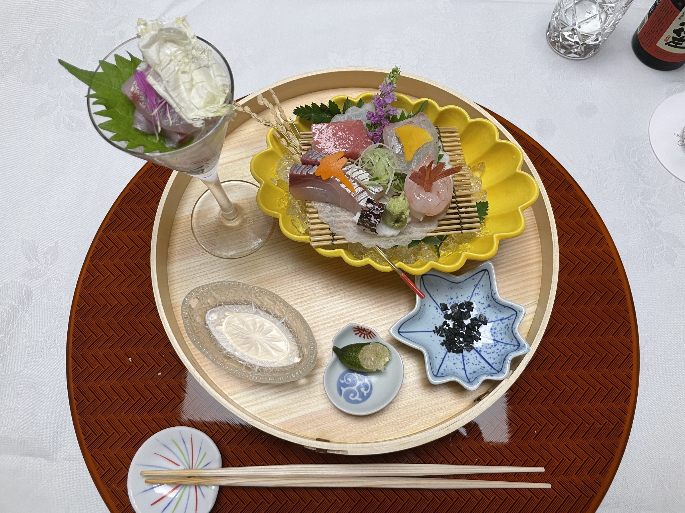 Sashimi, with a glass at top left holding fish dressed with oboro kombu.